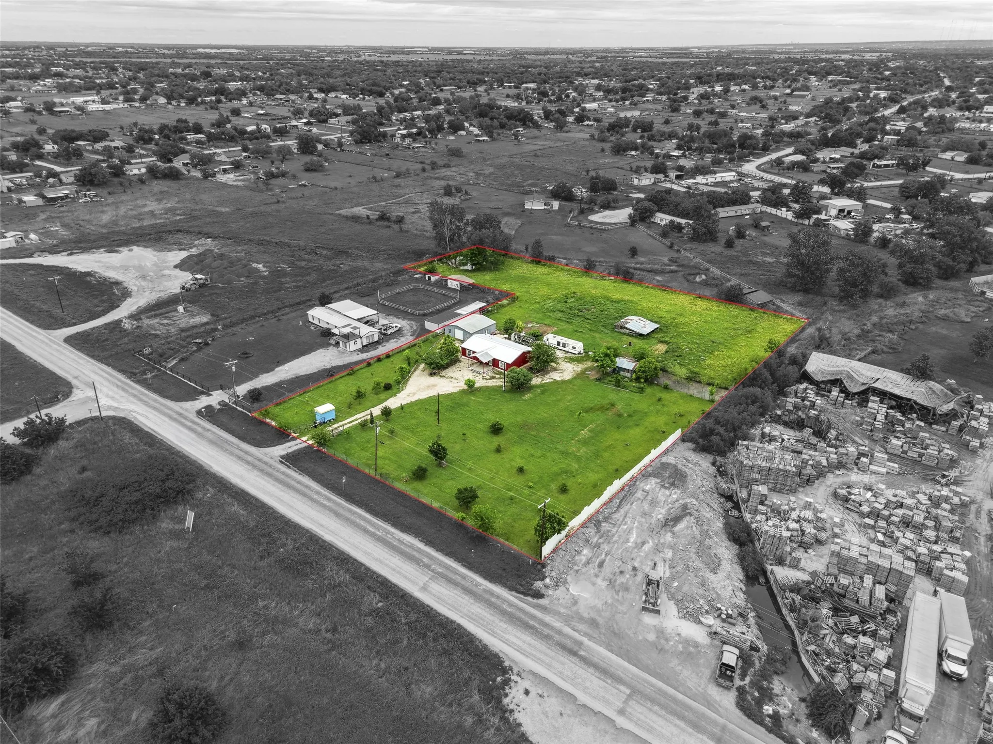Expansive land parcel featuring multiple structures, road frontage, and a substantial grassy area