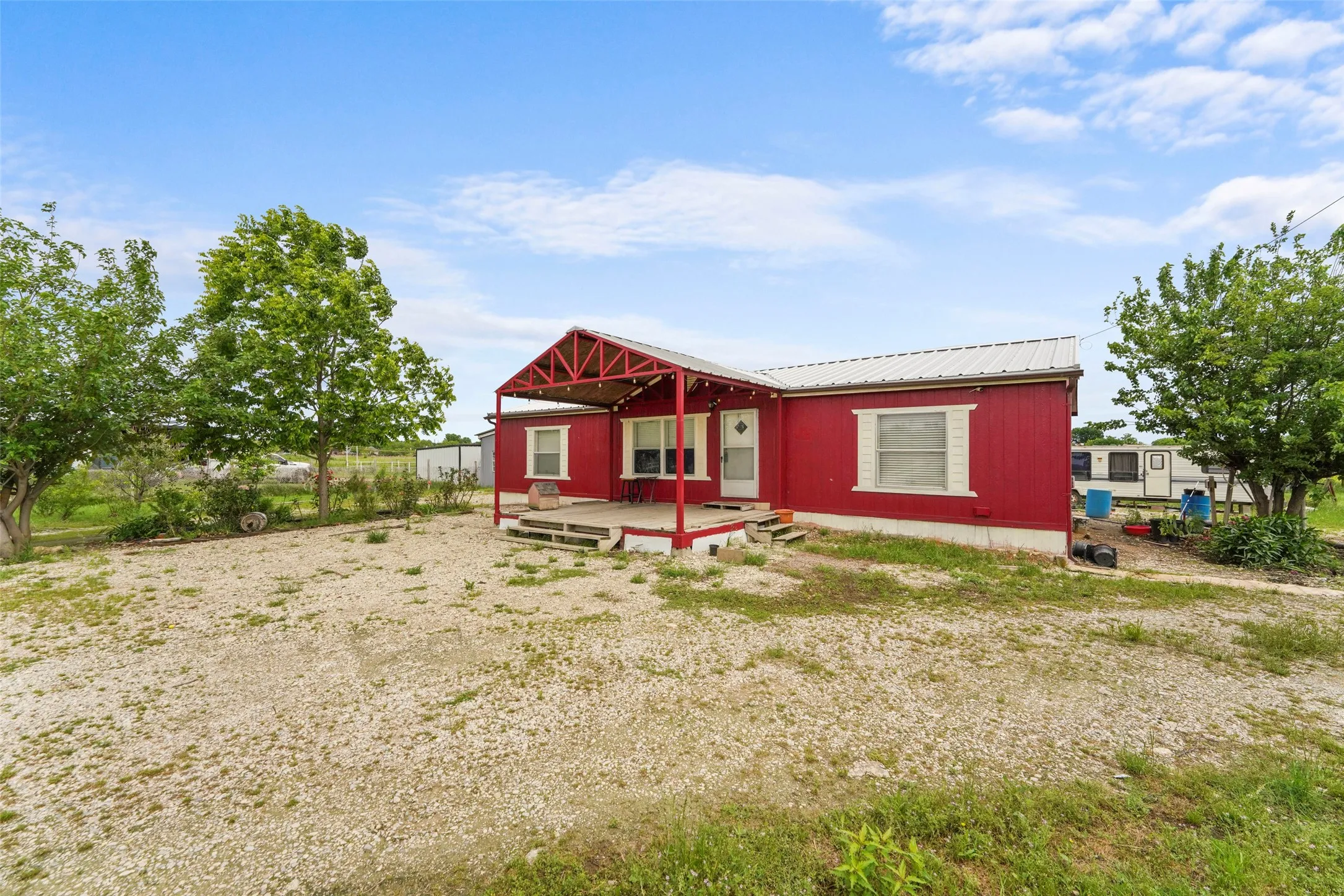 Red-sided residence featuring a covered front porch with a red metal roof structure