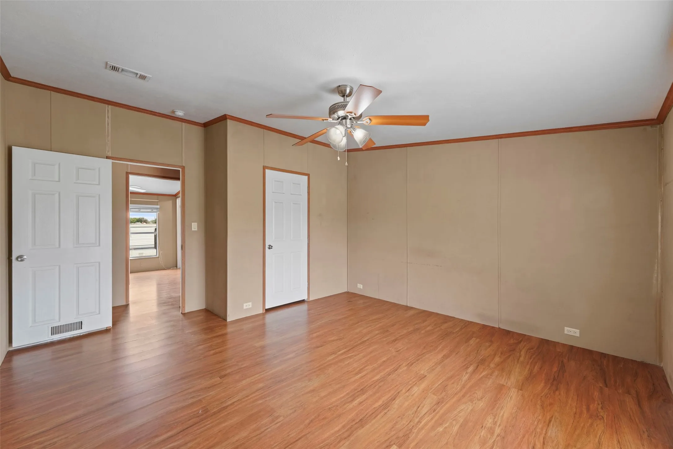 Spacious room featuring wood-finish flooring and a ceiling fan with integrated lighting