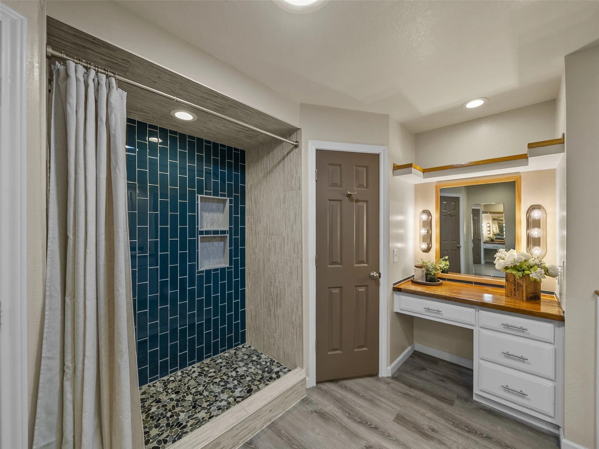 The oversized shower has built in shelving and showcases a river rock floor.
