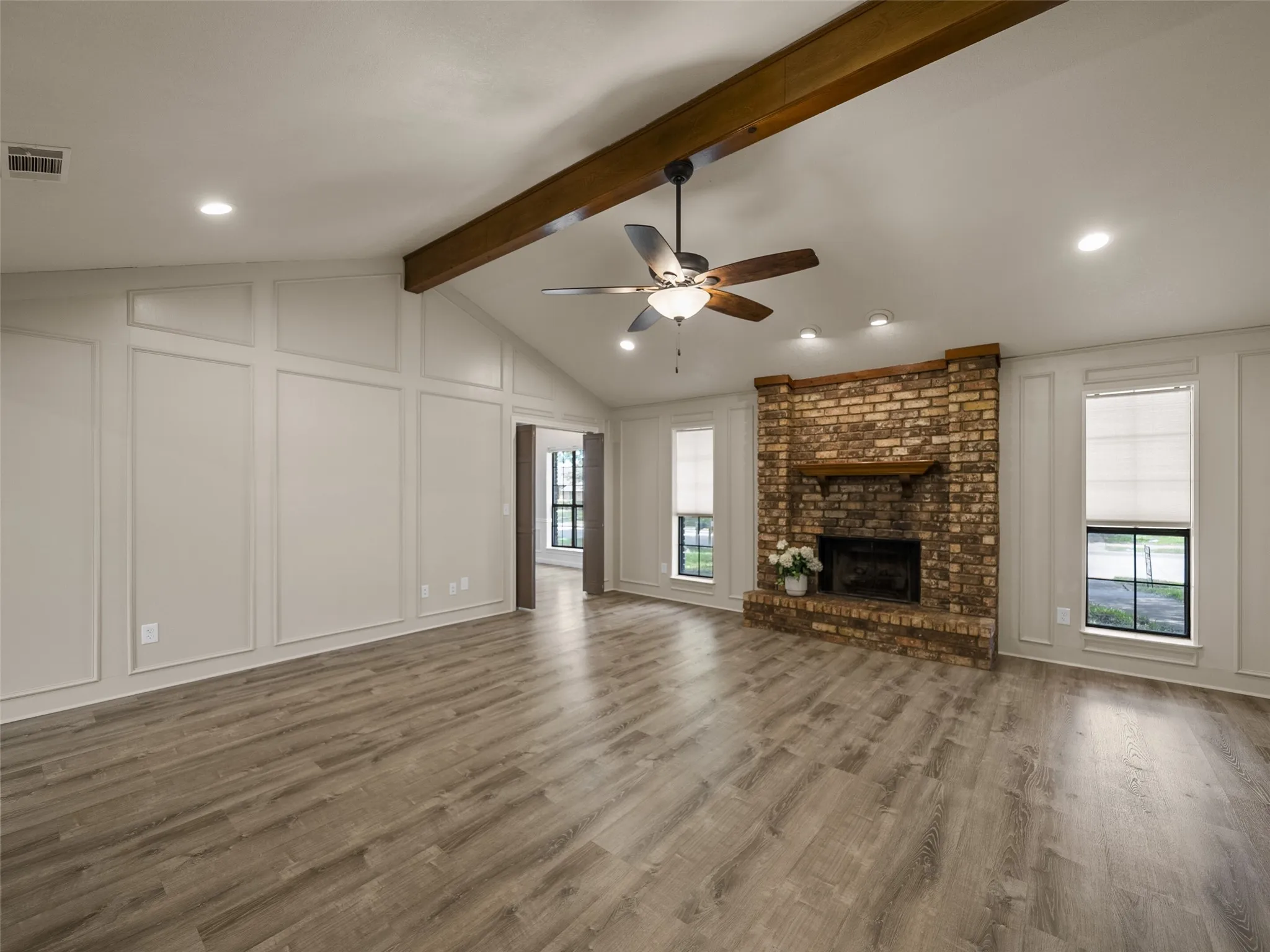 The masonry fireplace with gas starter is flanked by two windows and the room is accentuated with a wood-beamed cathedral ceiling.  Picture frame paneling surrounds the walls.