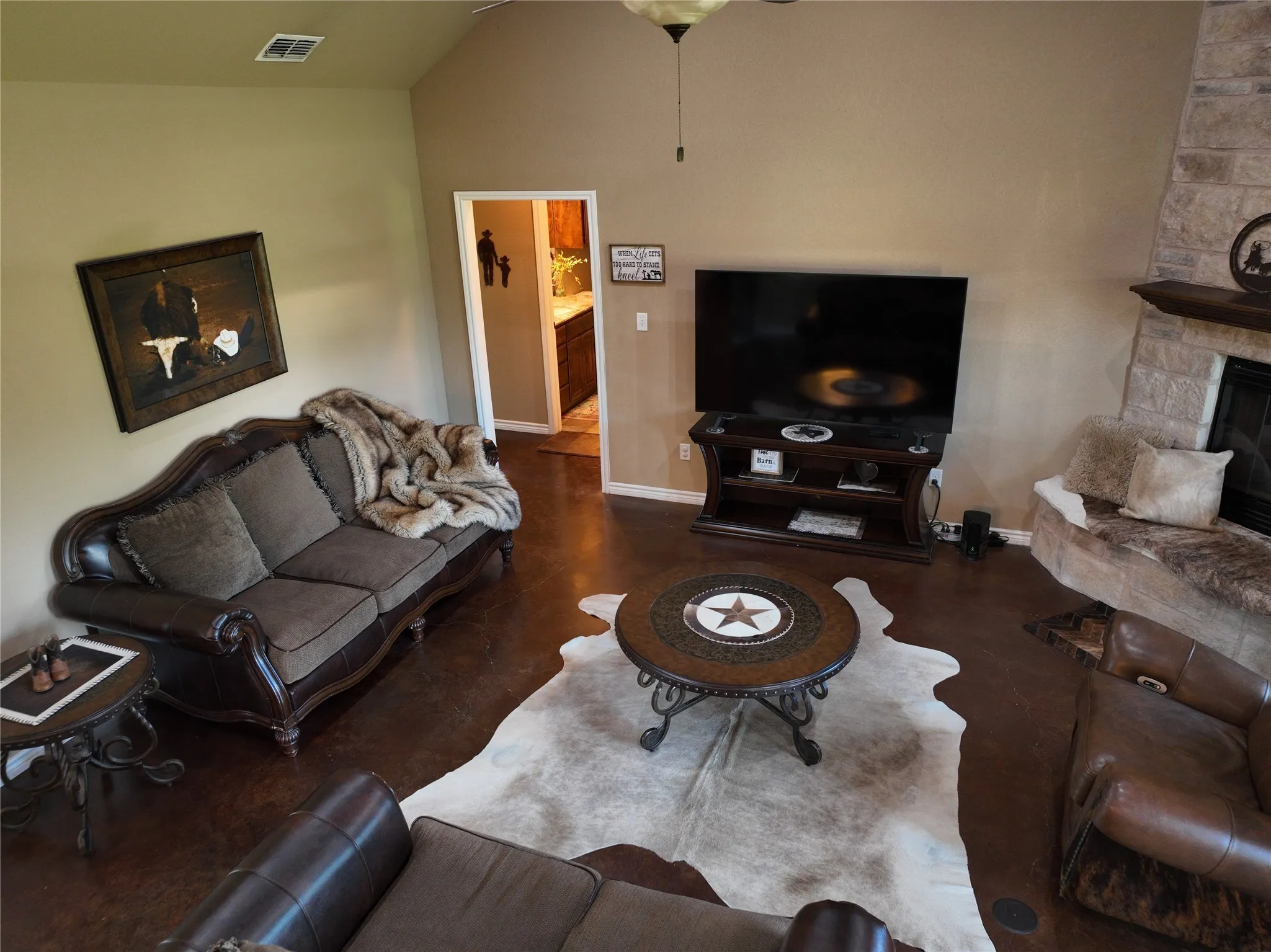 overhead into the living room with stone woodburning fireplace and stain concrete floors