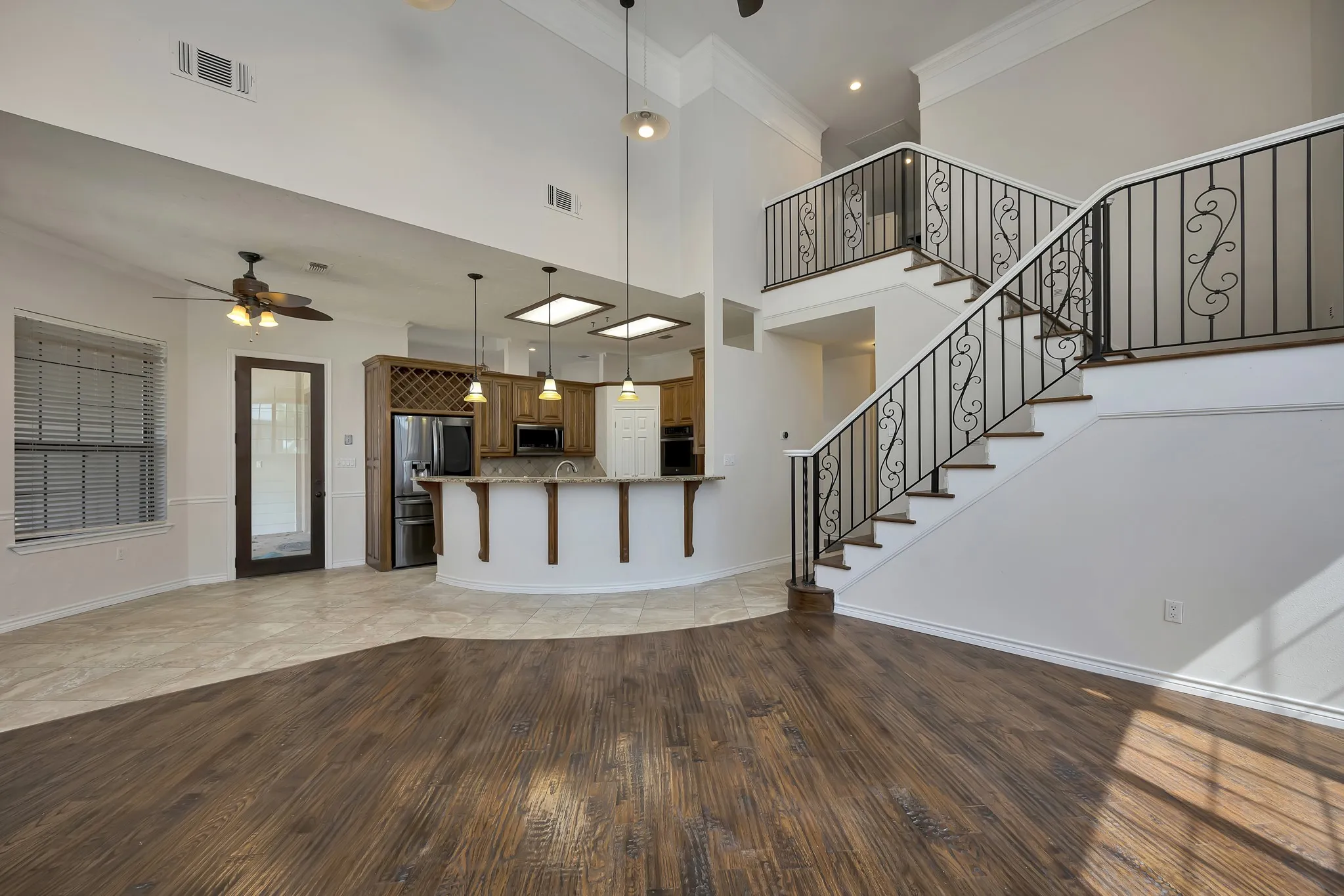 Unfurnished living room featuring light wood-type flooring, a ceiling fan, ornamental molding, and stairway