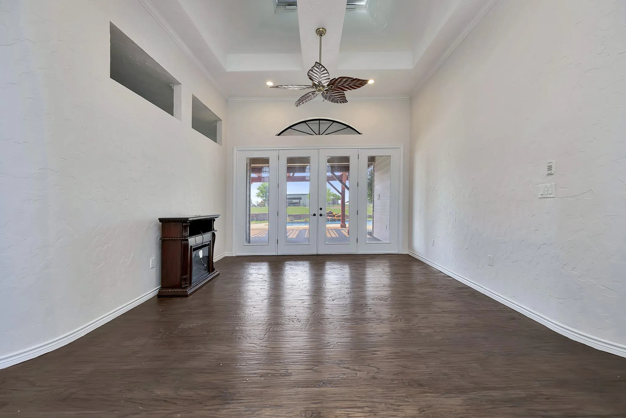 Unfurnished living room featuring dark wood-style floors, french doors, a towering ceiling, and crown molding