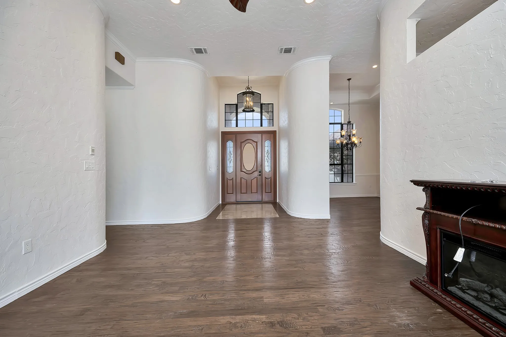 Entryway with a textured wall, a chandelier, wood finished floors, and a textured ceiling