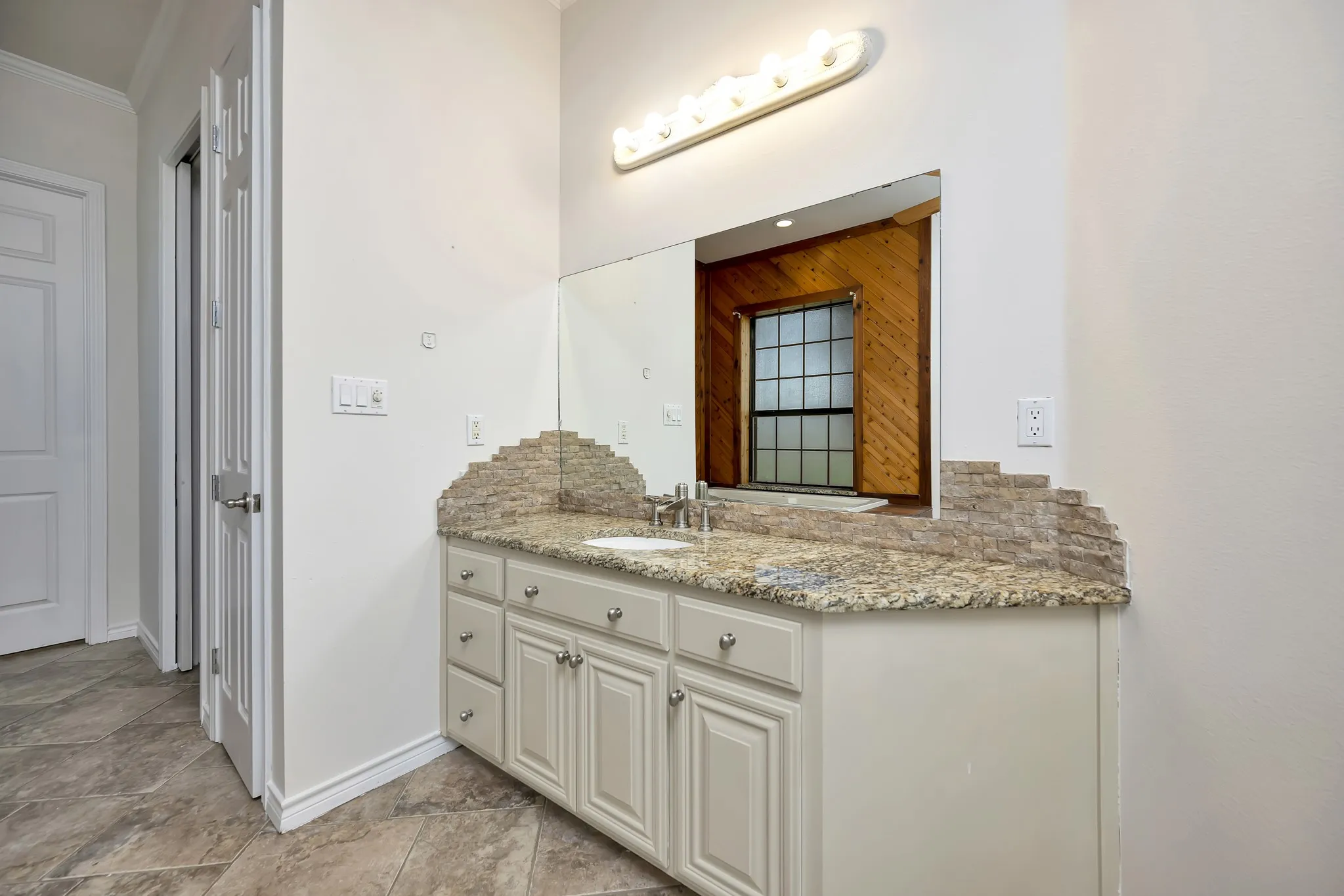 Bathroom featuring vanity, ornamental molding, and stone finish floors