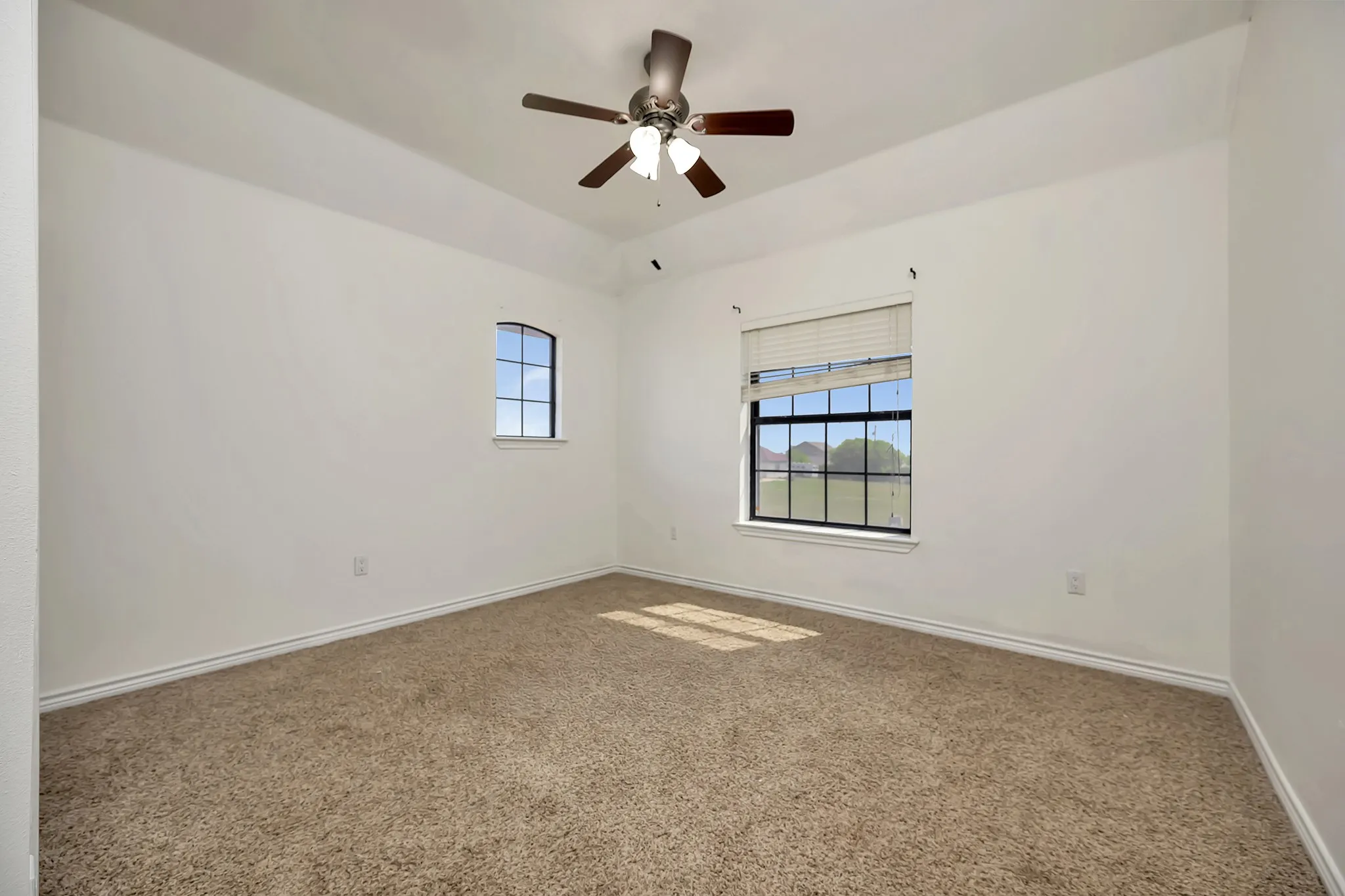 Carpeted empty room featuring baseboards and ceiling fan