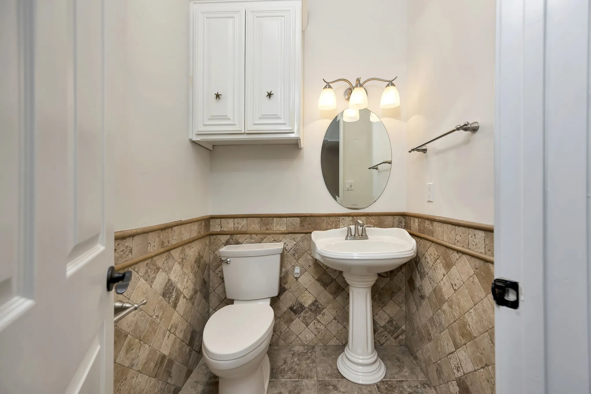 Bathroom with a wainscoted wall and tile walls