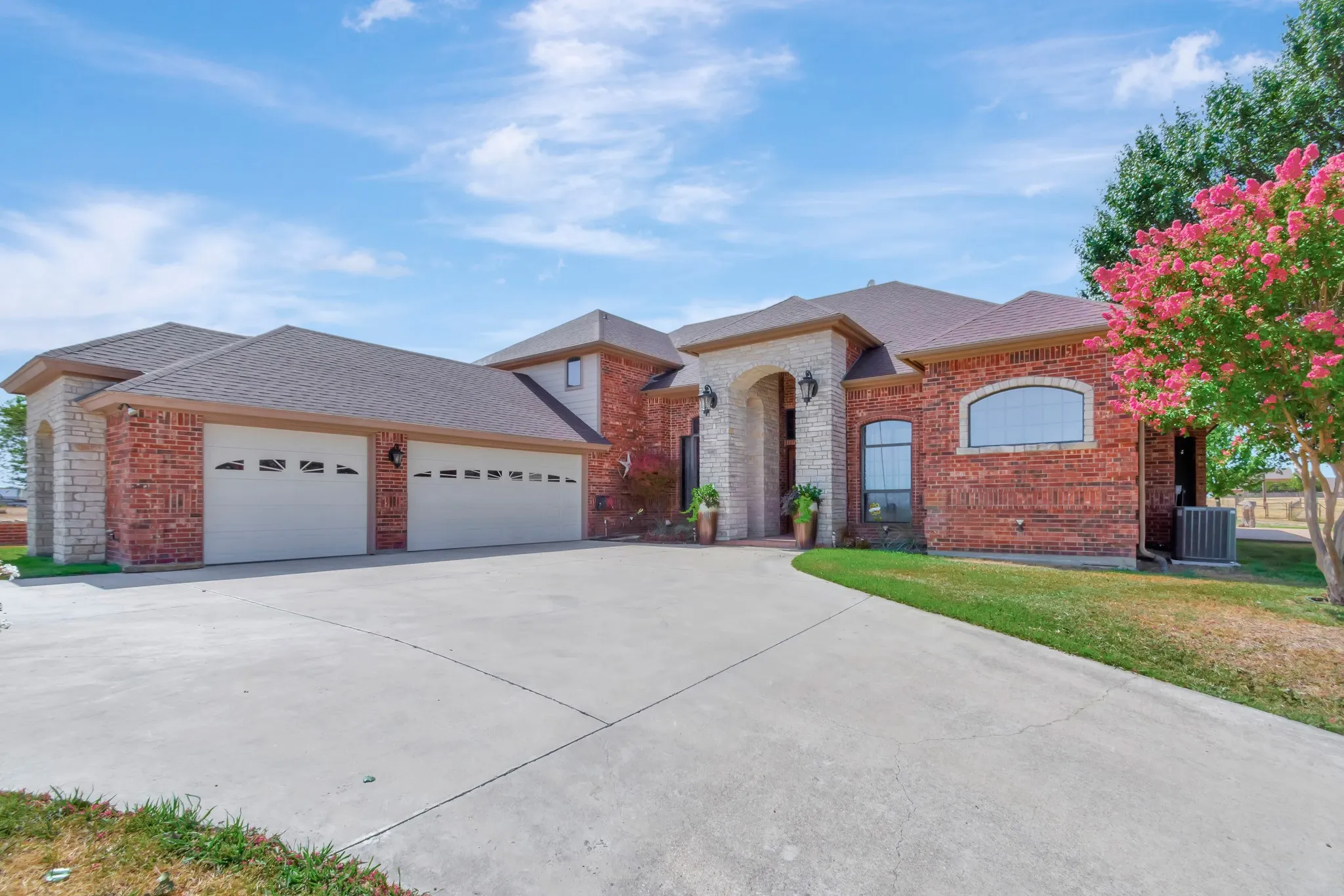 View of front of house featuring driveway, an attached garage, brick siding, a front yard, and a shingled roof
