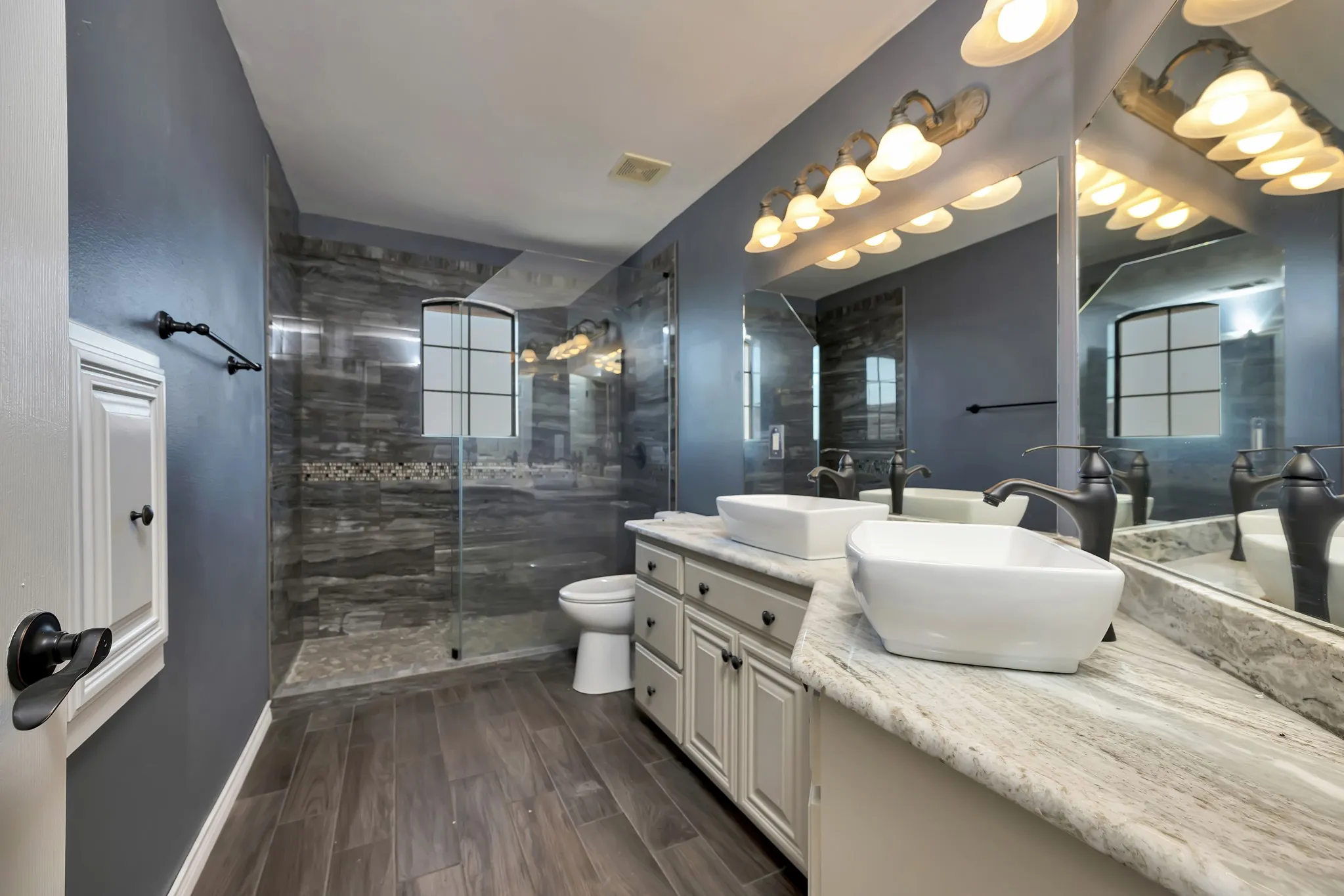 Full bathroom with plenty of natural light, double vanity, a stall shower, and wood finished floors