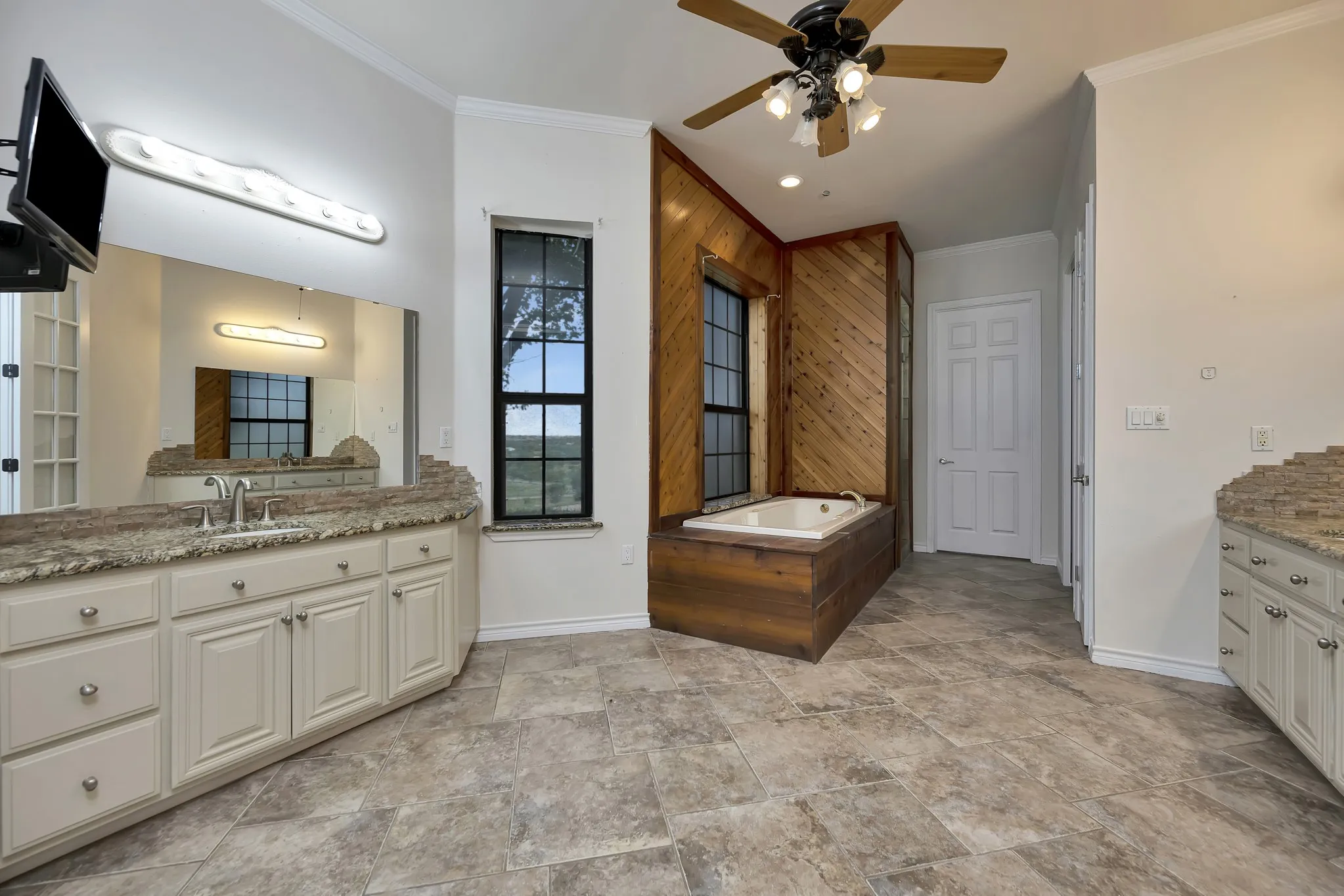 Bathroom featuring ornamental molding, ceiling fan, vanity, stone finish flooring, and a bath