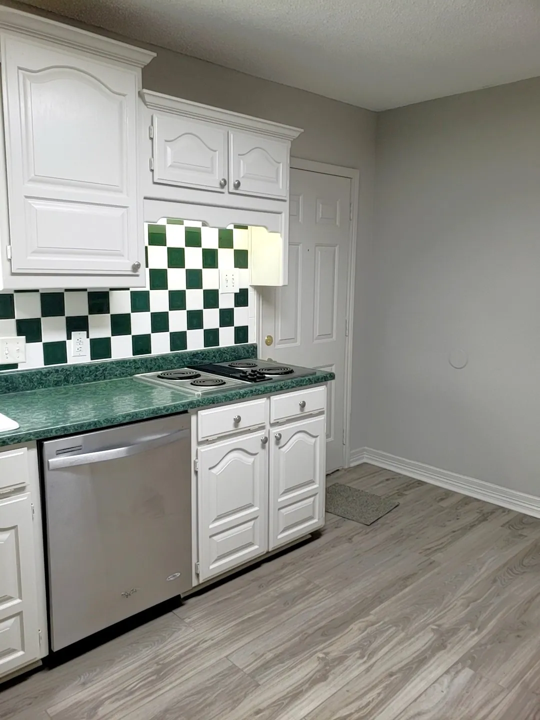 Kitchen featuring white cabinetry, green countertops, and a black and white checkerboard tile backsplash