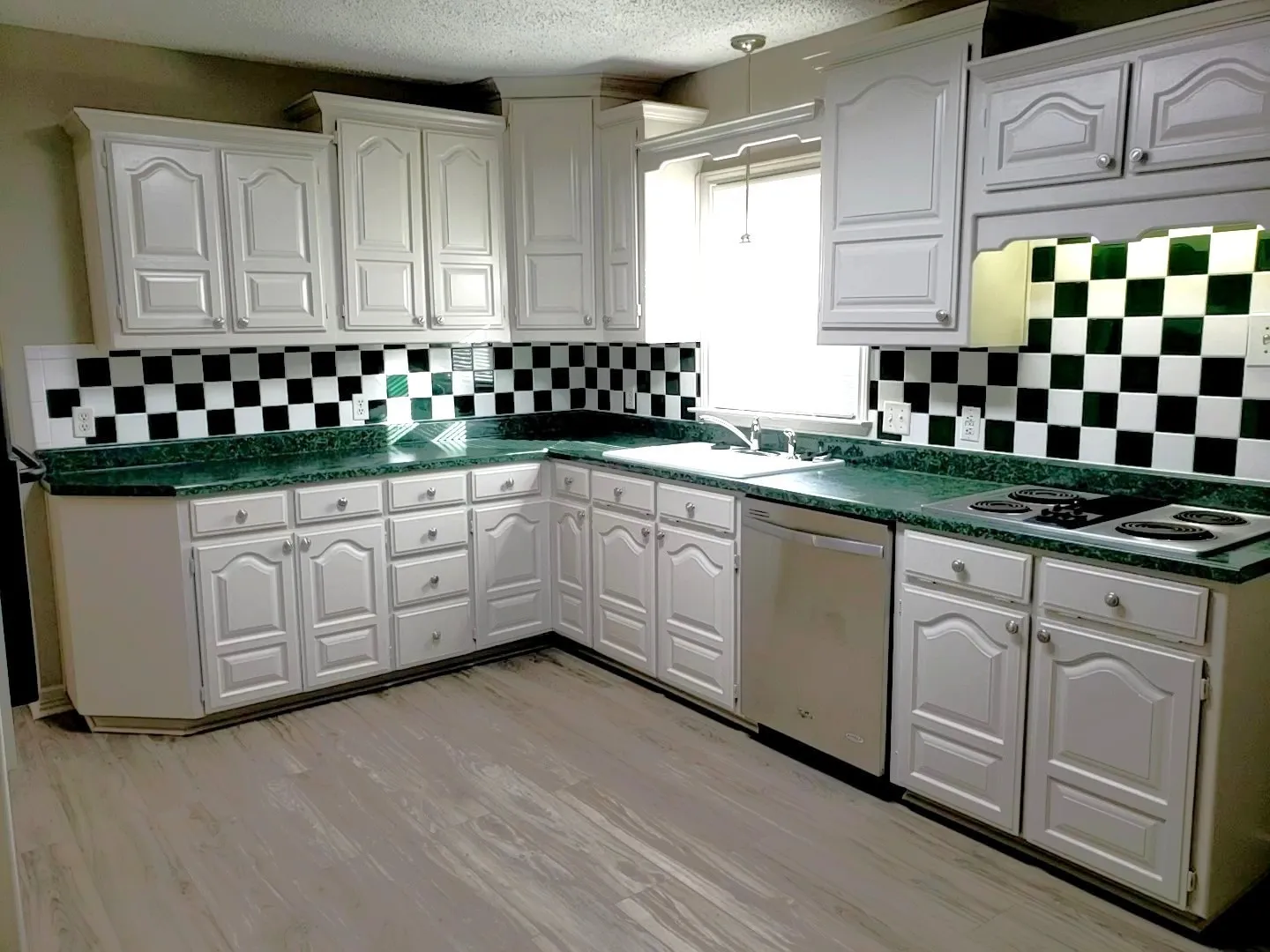 Kitchen featuring white cabinetry, green countertops, and a black and white checkerboard tile backsplash