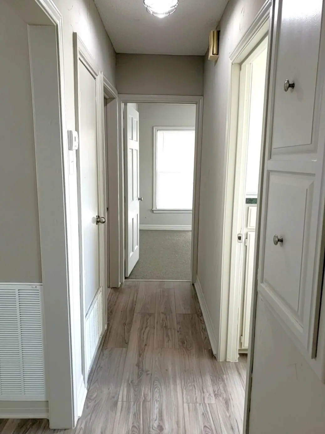 Hallway featuring white paneled doors & light fixture