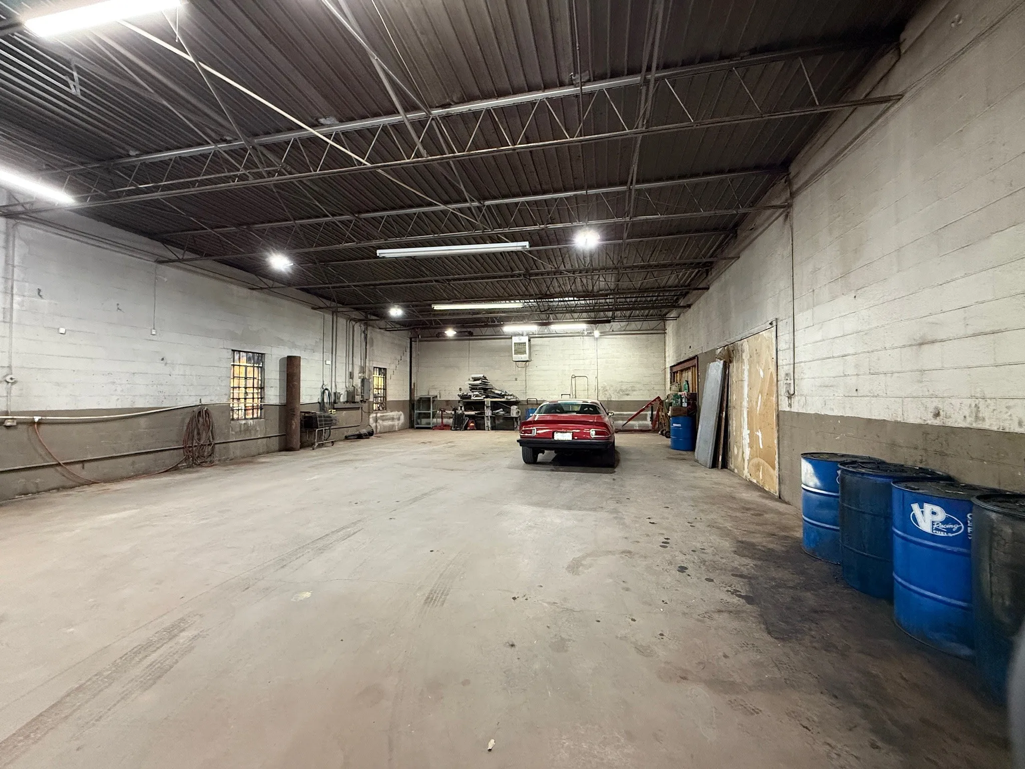 Expansive industrial interior featuring concrete flooring and exposed metal ceiling trusses