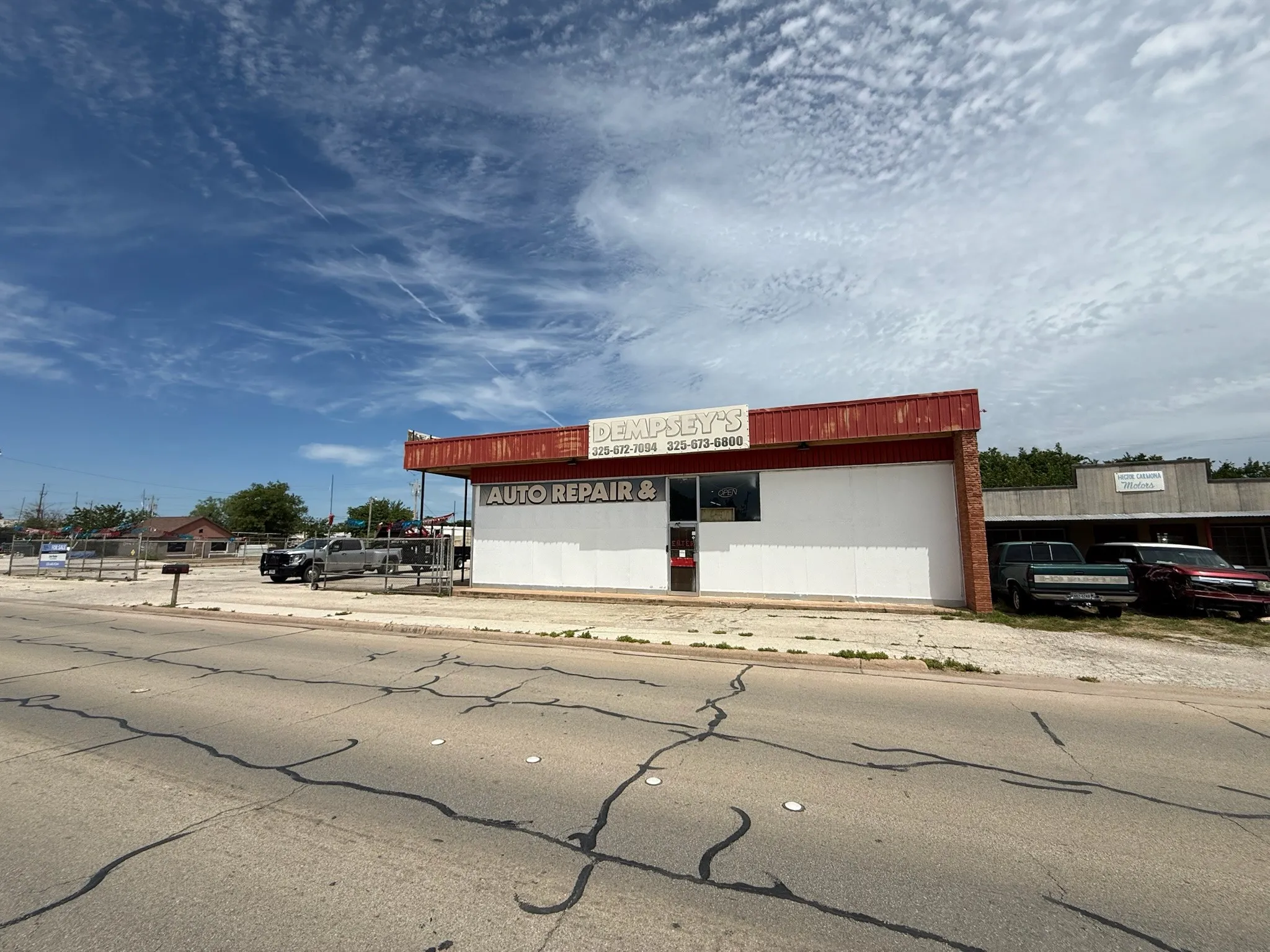 Commercial building featuring a red metal awning, white exterior siding, and a prominent storefront sign