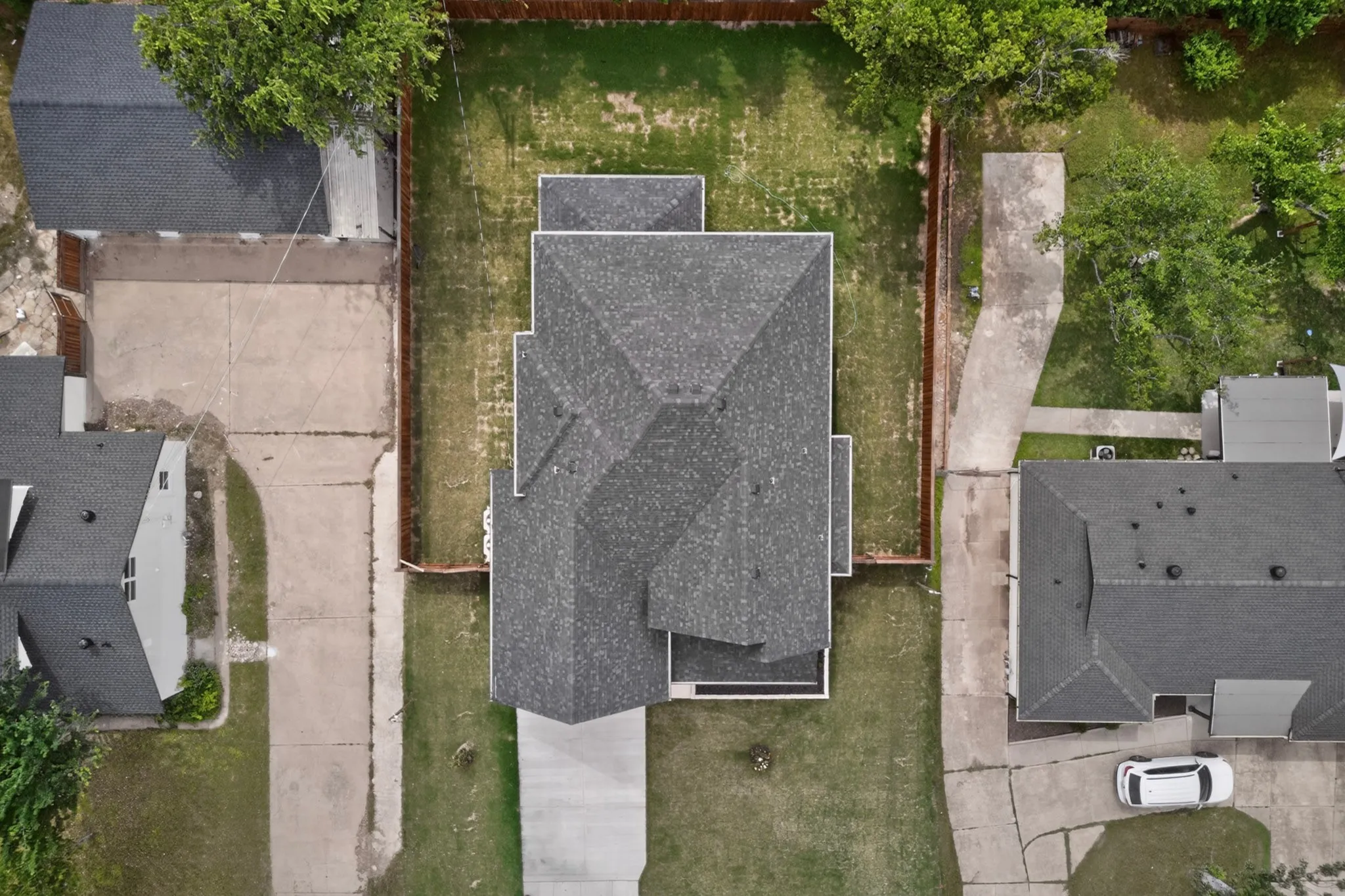 Main residence with a dark shingle roof and a concrete driveway