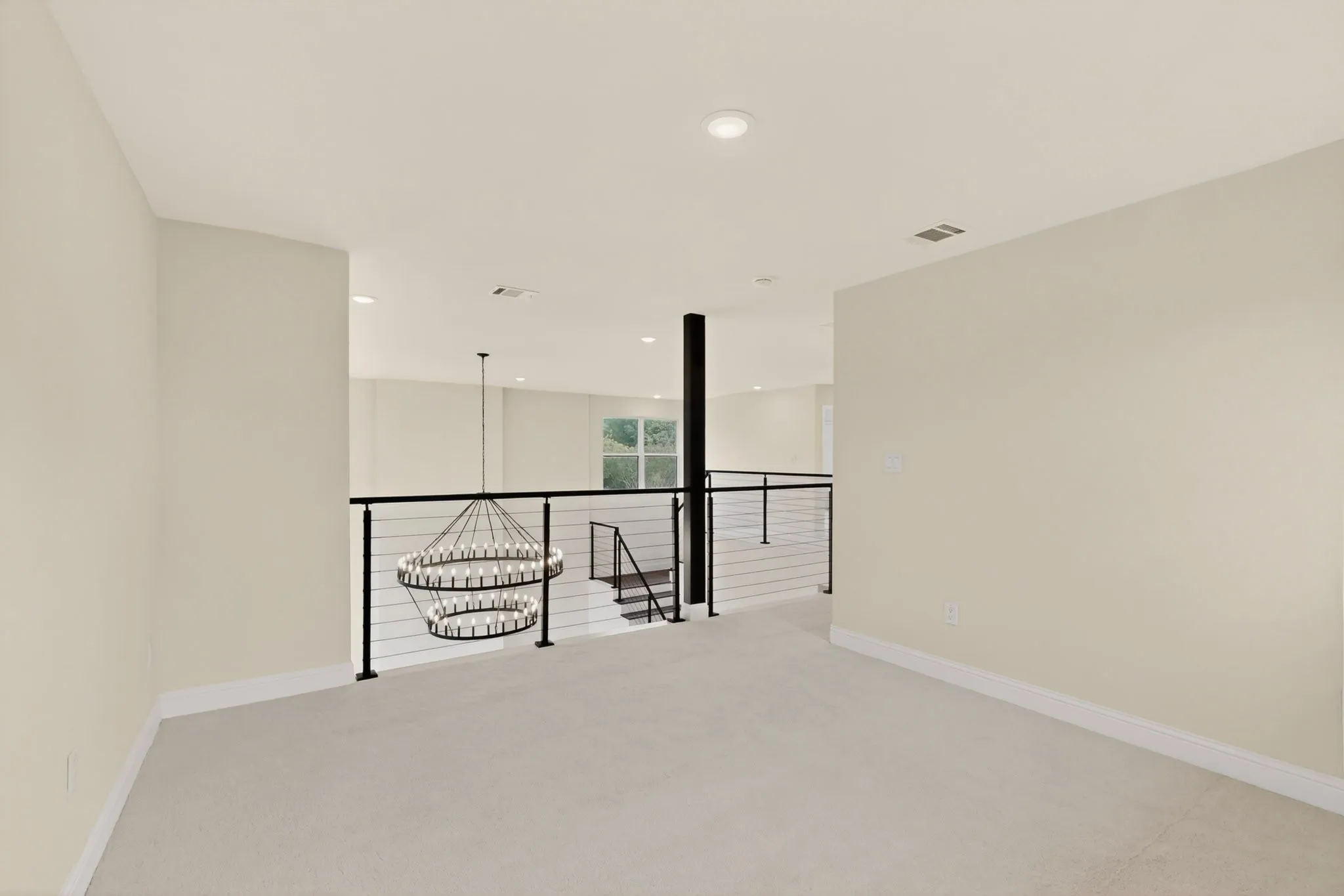 Upper-level landing featuring neutral carpeting, recessed ceiling lighting, and a contemporary chandelier