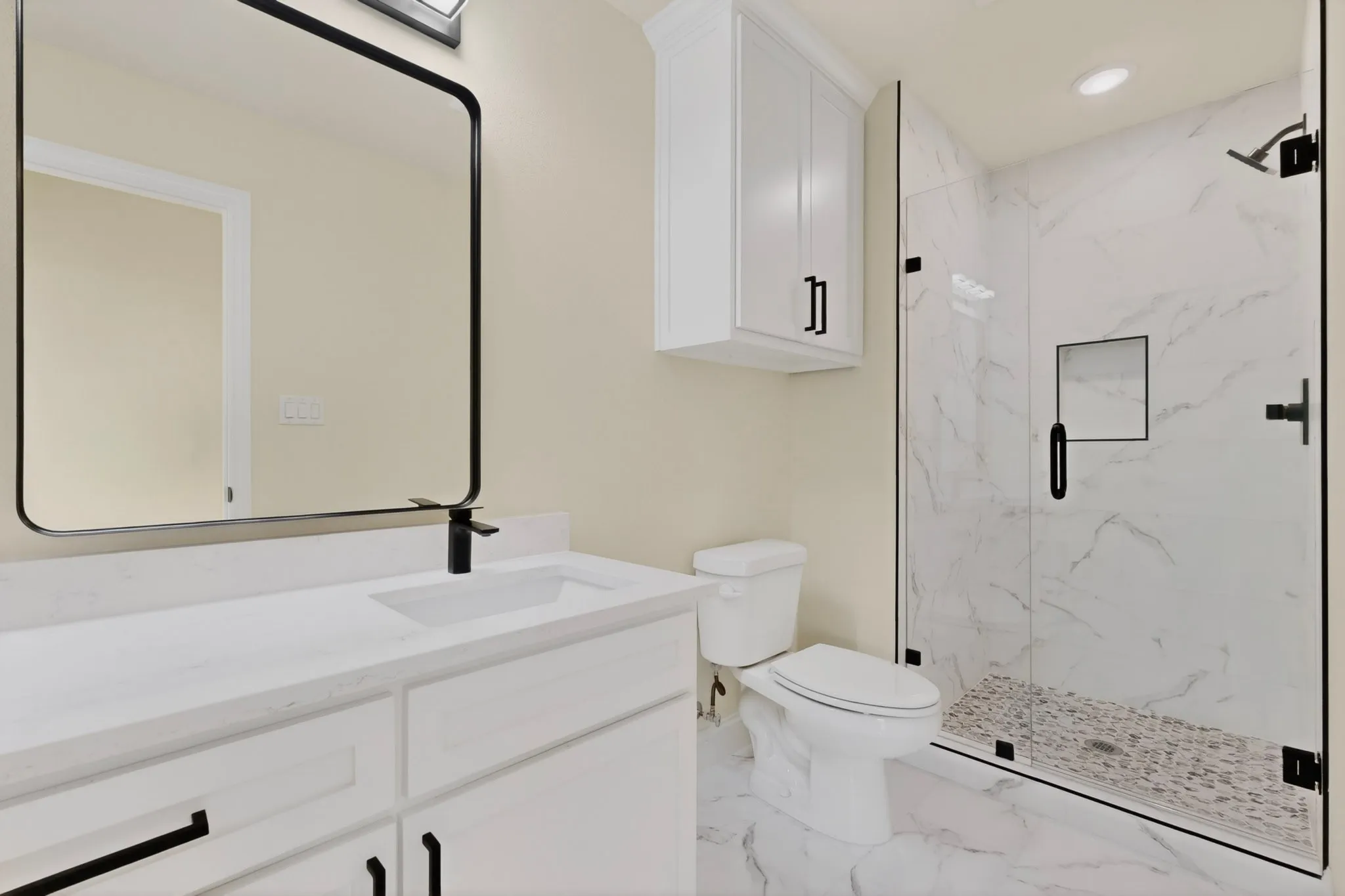 Bathroom featuring a white vanity with an integrated sink, black faucet, and a large framed mirror