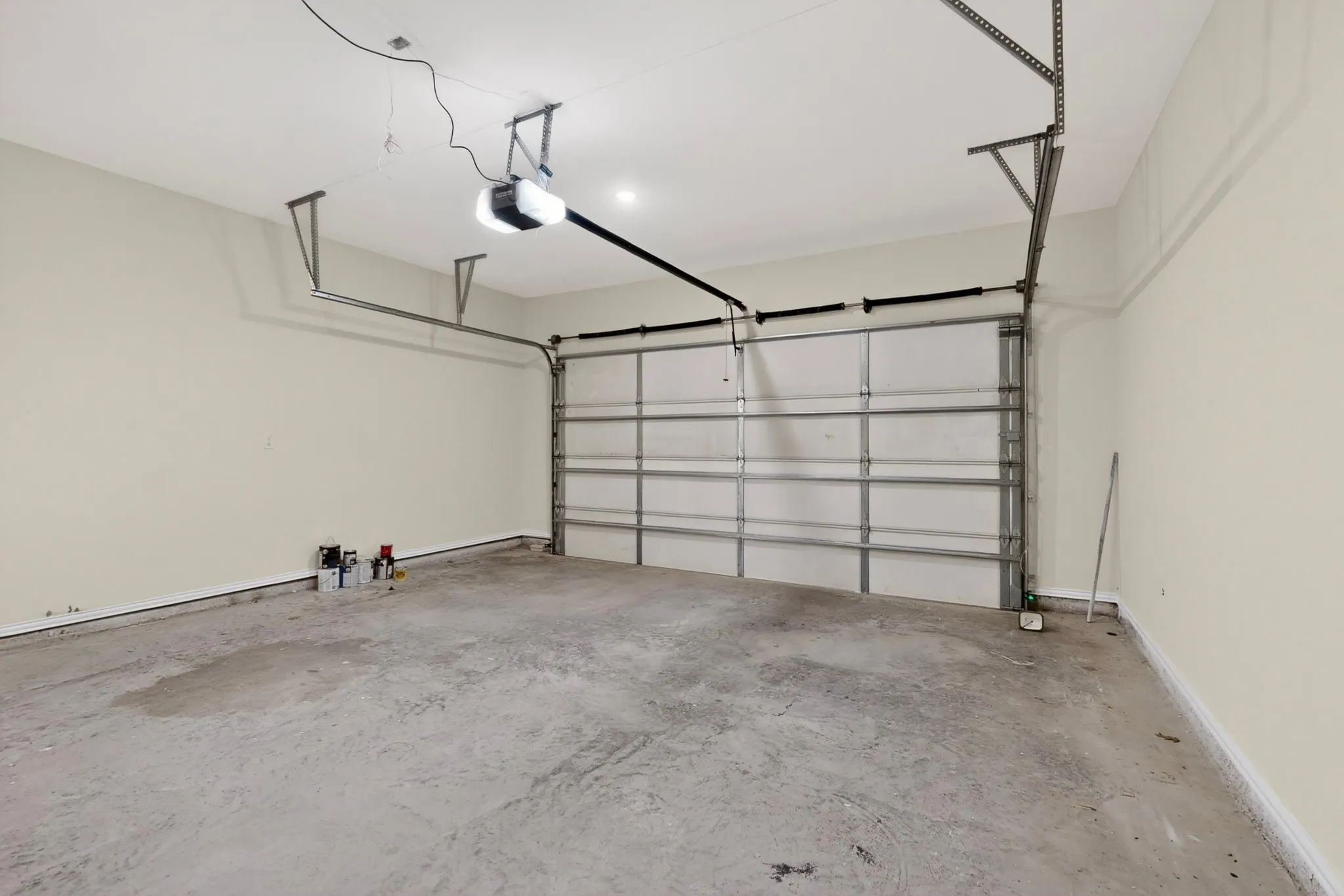 Attached garage featuring a concrete floor, light-toned walls, a sectional garage door, and an overhead garage door opener