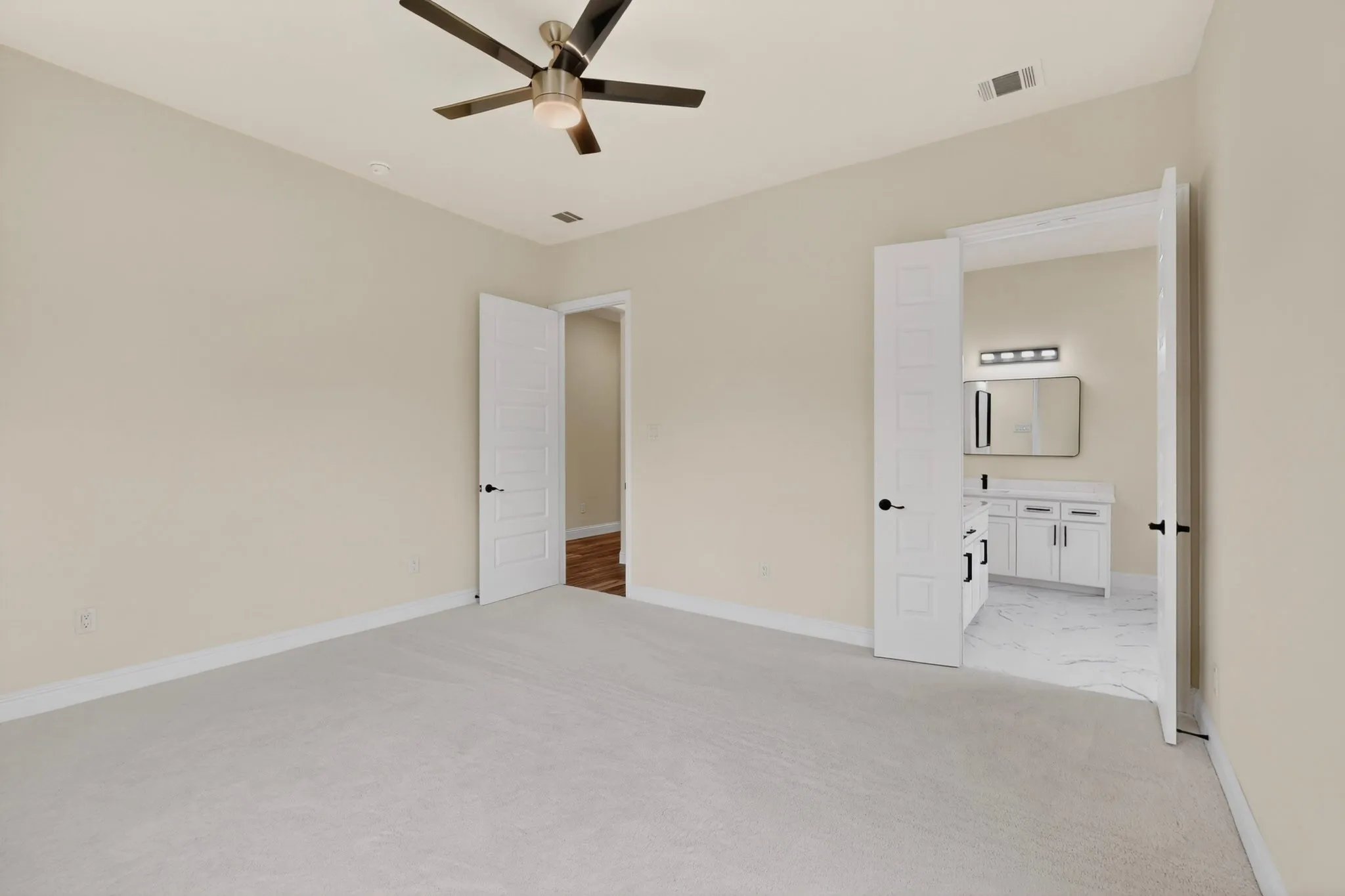 Neutral-toned room featuring a ceiling fan with integrated lighting, light carpet flooring, and white trim