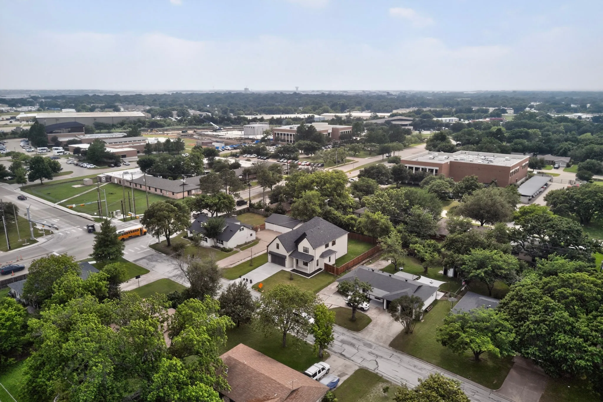 Aerial perspective of a neighborhood featuring a two-story residence with a dark roof and light-colored siding