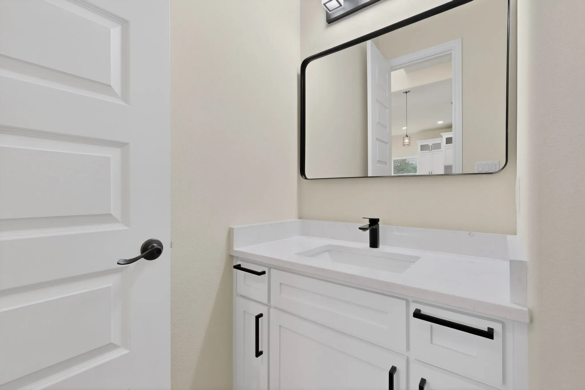 White shaker-style vanity with stone-finish countertop, undermount sink, and matte black faucet
