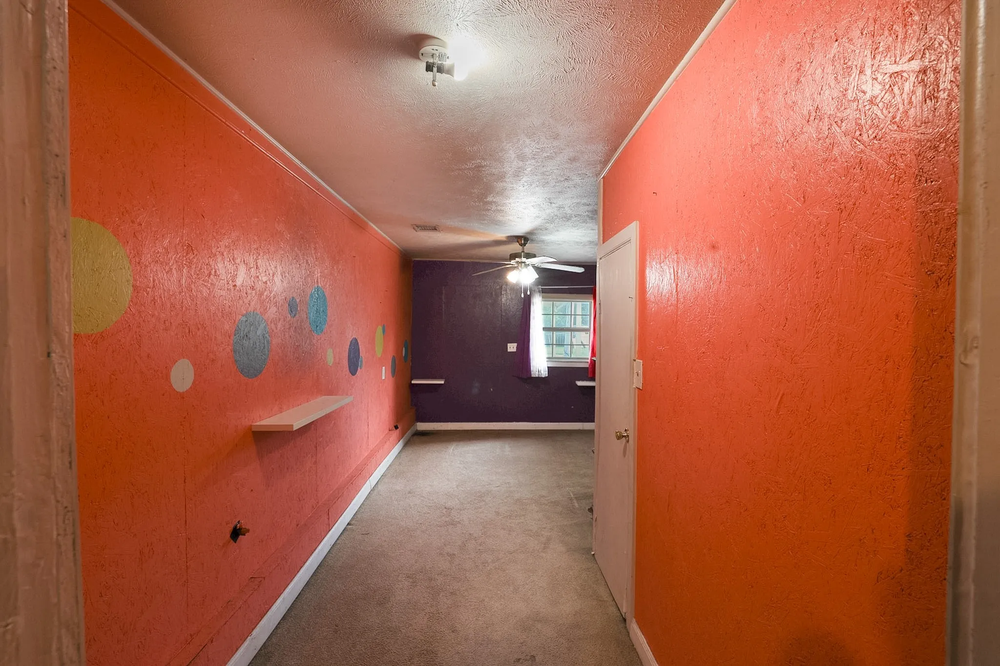 Hallway featuring textured orange walls with circular accents and white trim
