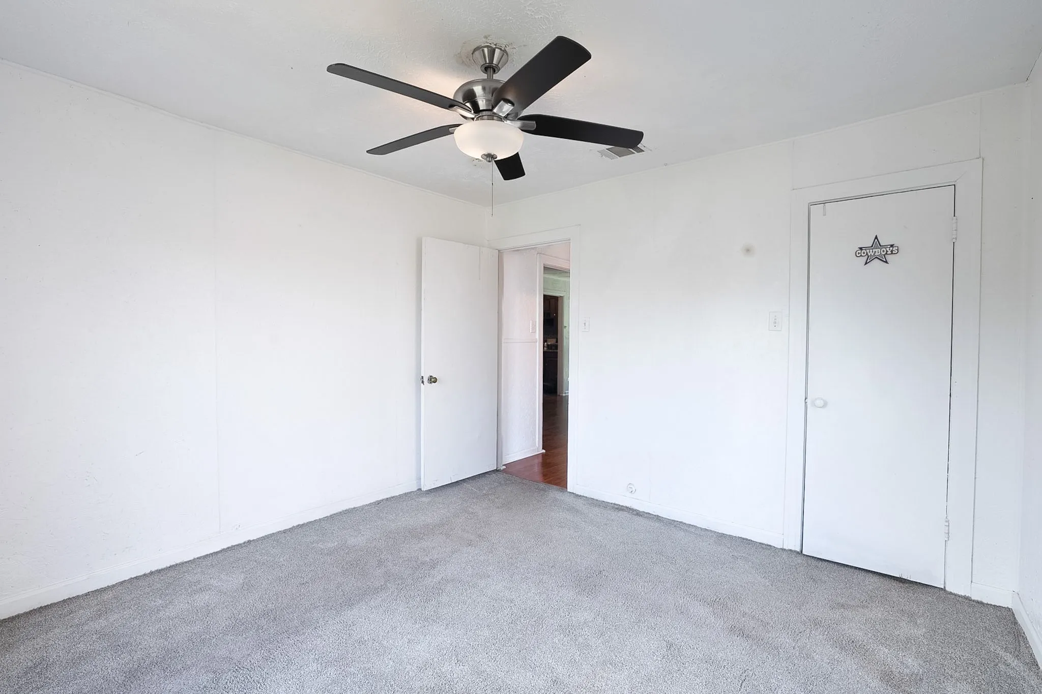 Room featuring light gray carpet, white walls, and a ceiling fan with light fixture