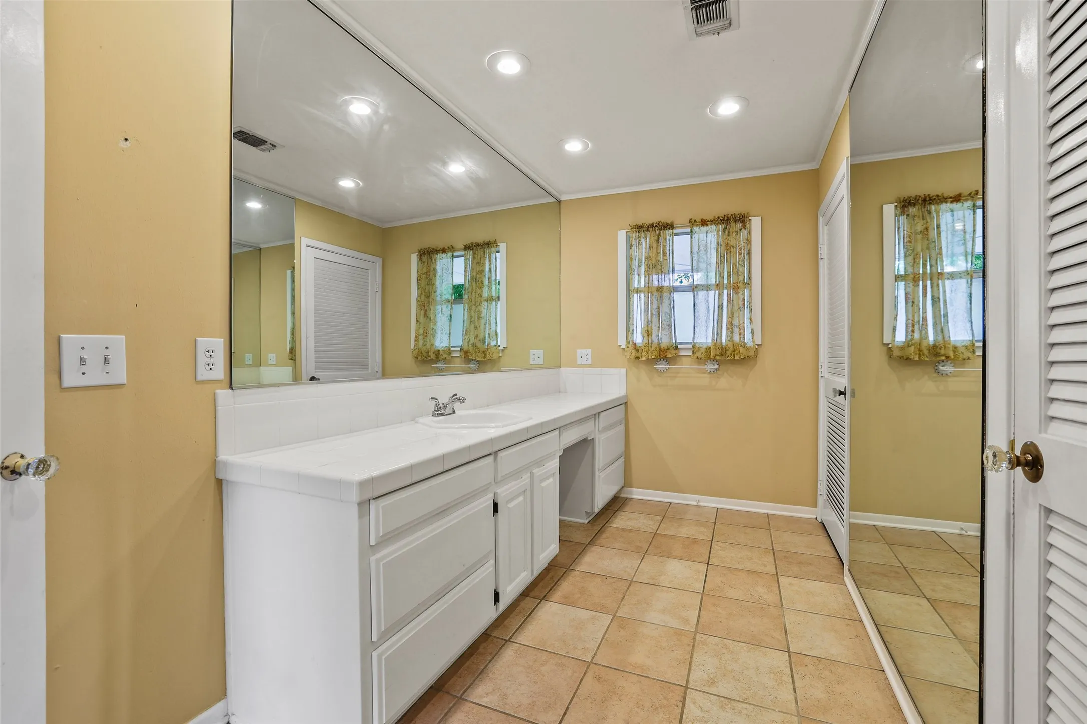Mirrored dressing area with two large walk-in closets in the primary bedroom