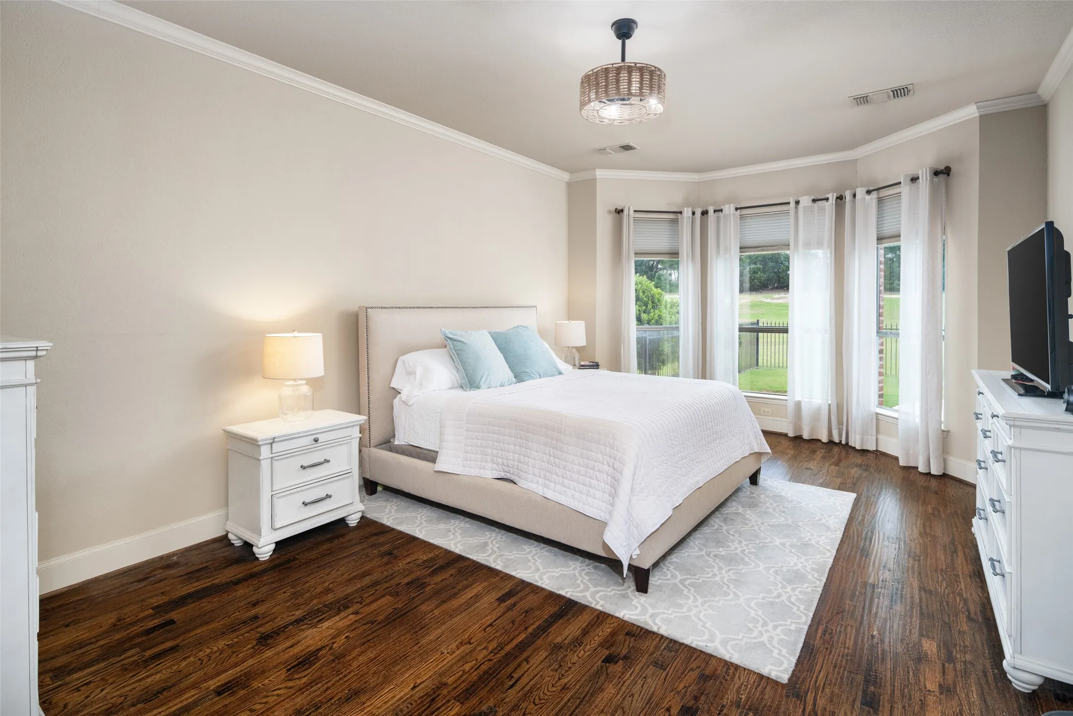 Serene and Luxurious Primary Bedroom has Extended Hardwoods, Tall Ceilings, Fandelier, Soothing Color Palette and Bay Windows