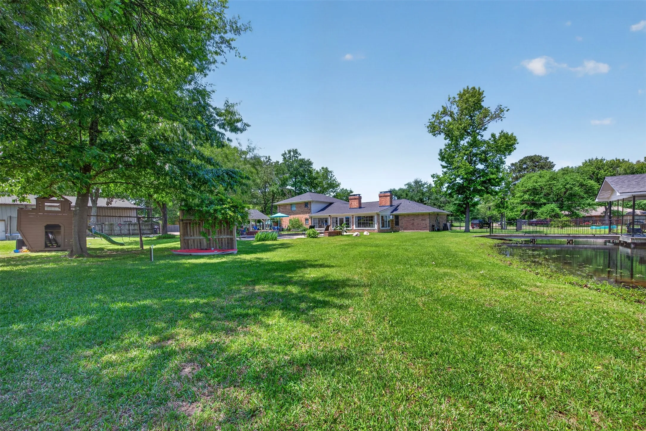 Expansive green lawn with mature trees and a waterfront setting