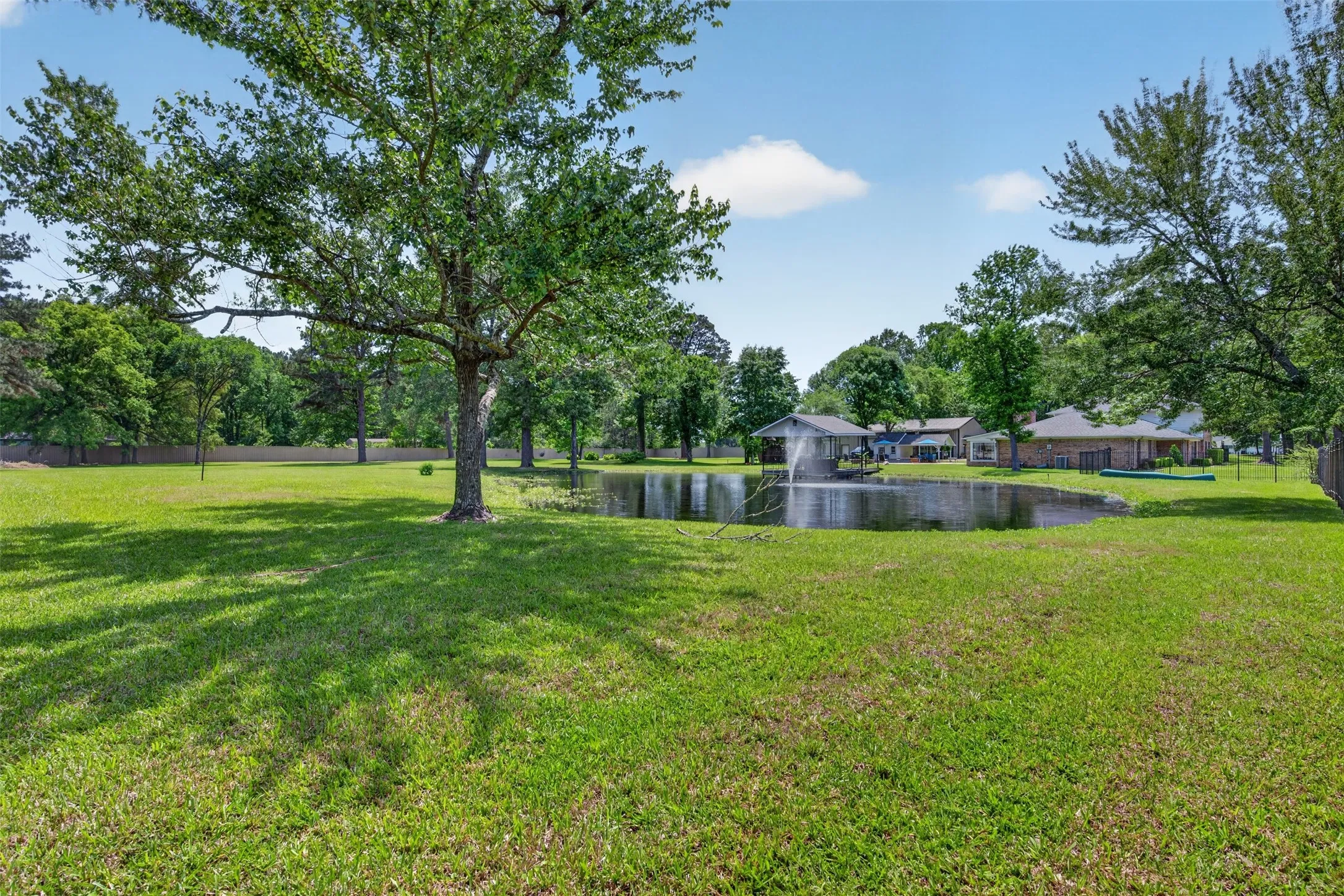 Expansive green lawn with mature trees and a private pond featuring a water fountain