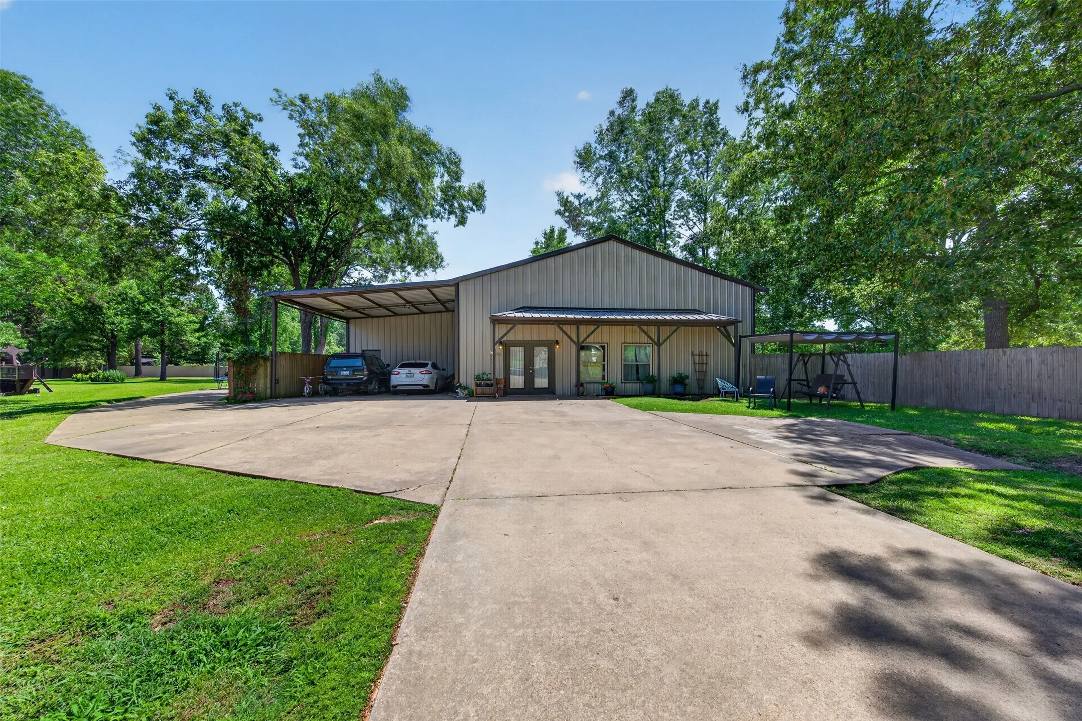 Metal-sided structure featuring a covered front porch with exposed wood beams and double-door entry