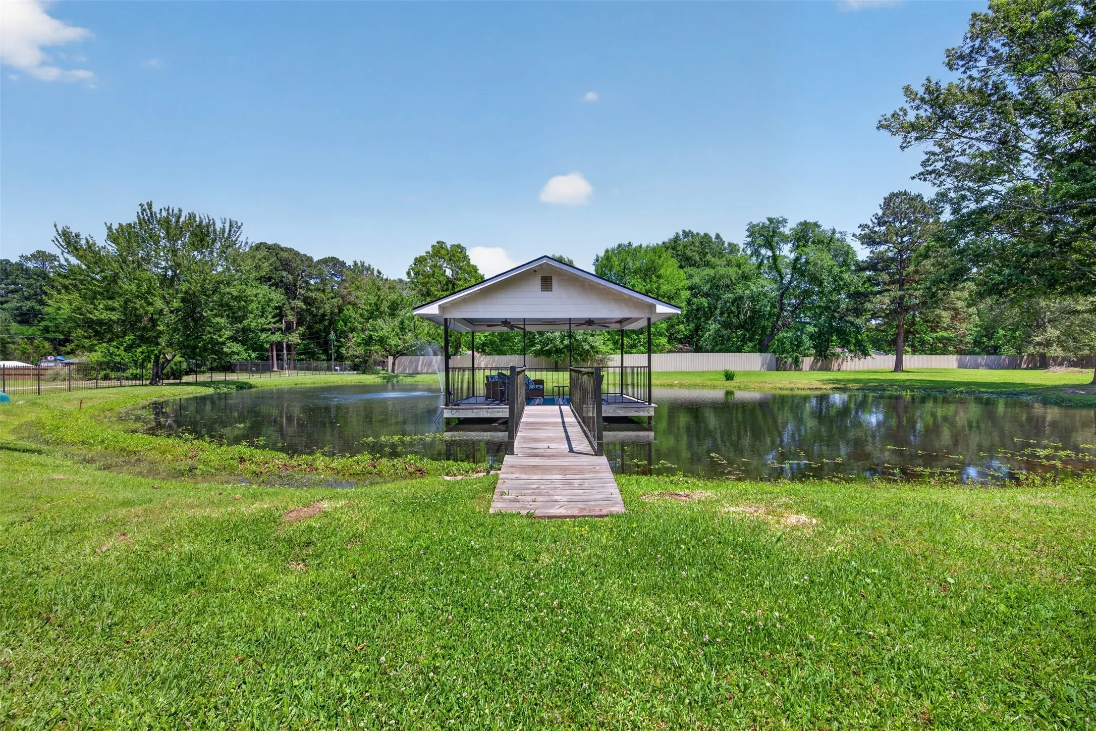 Expansive outdoor space featuring a covered boat dock, private pond with a fountain, and a wooden walkway