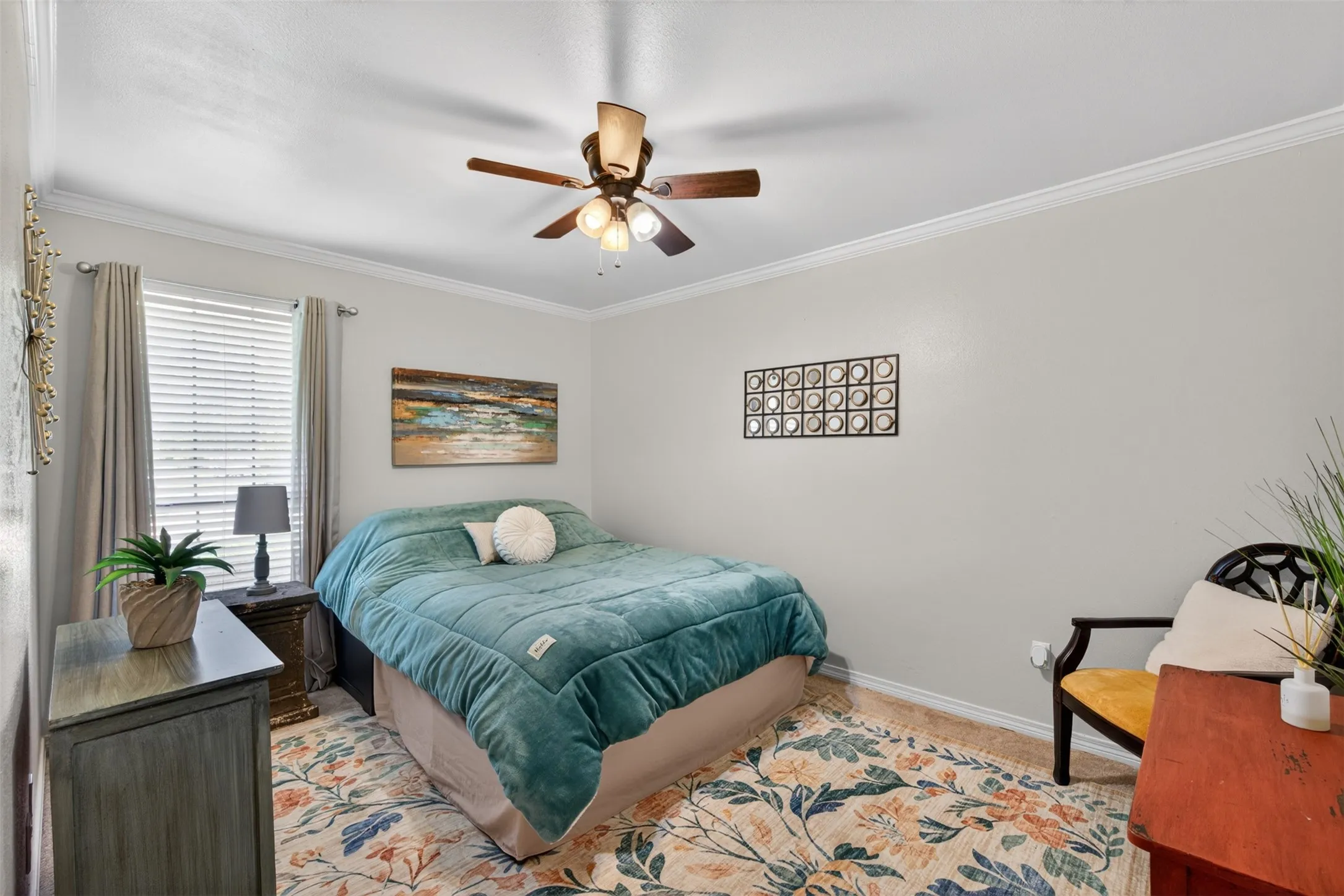Room featuring a window with blinds and drapes, a ceiling fan with integrated lighting, crown molding, and a patterned area rug