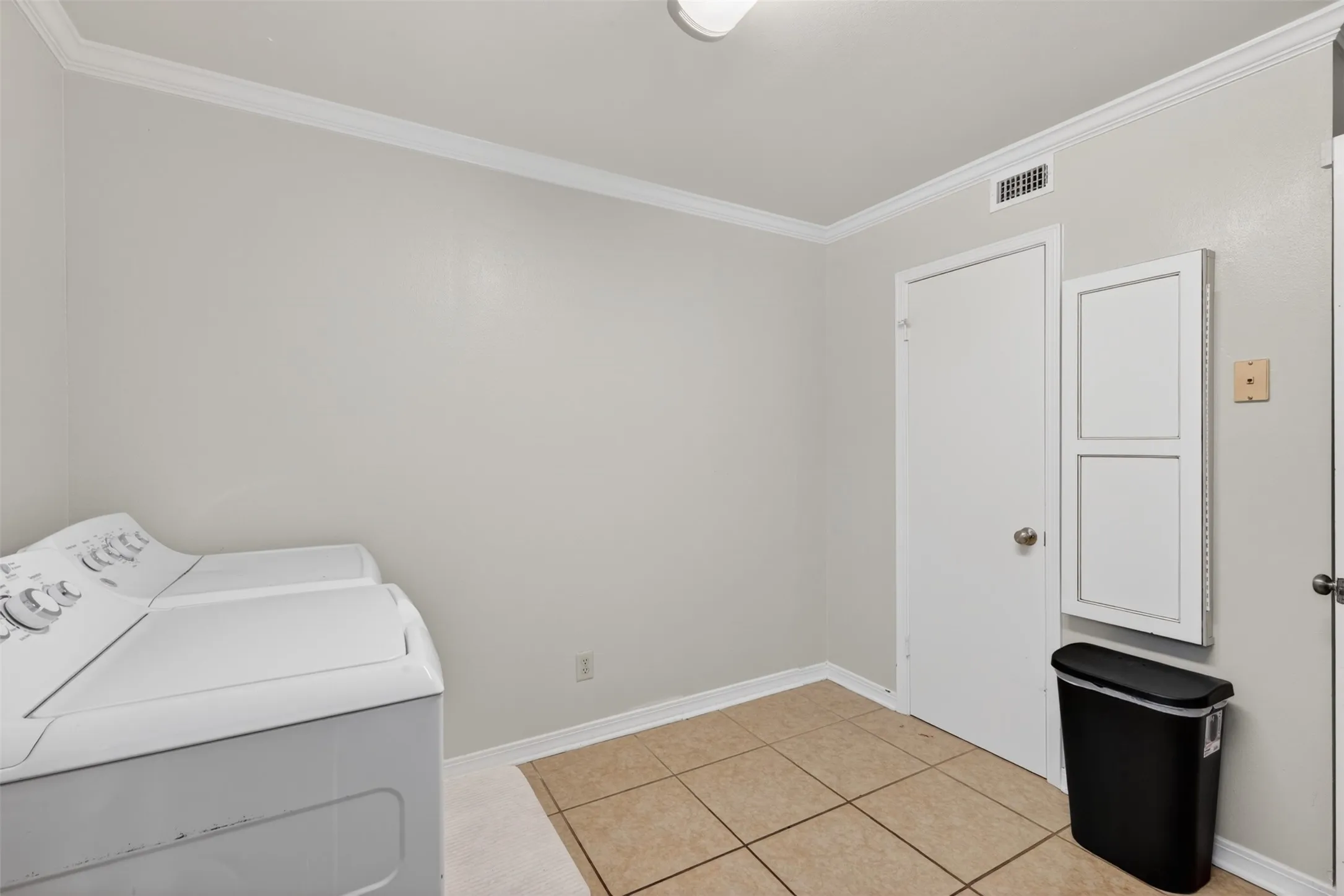 Dedicated utility space featuring tile flooring and crown molding