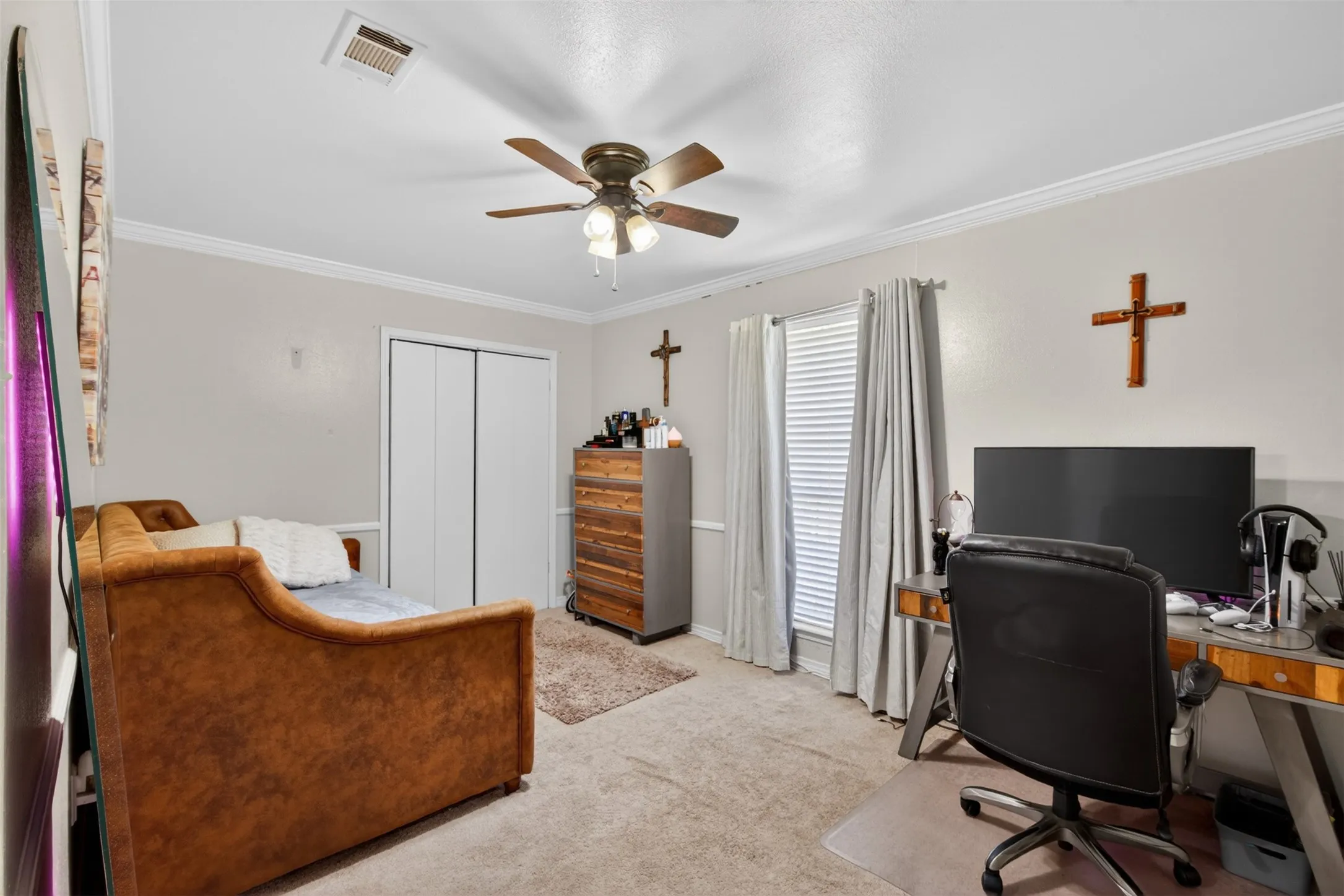 Carpeted room featuring a ceiling fan with integrated lighting, crown molding, and dual windows with blinds and drapes