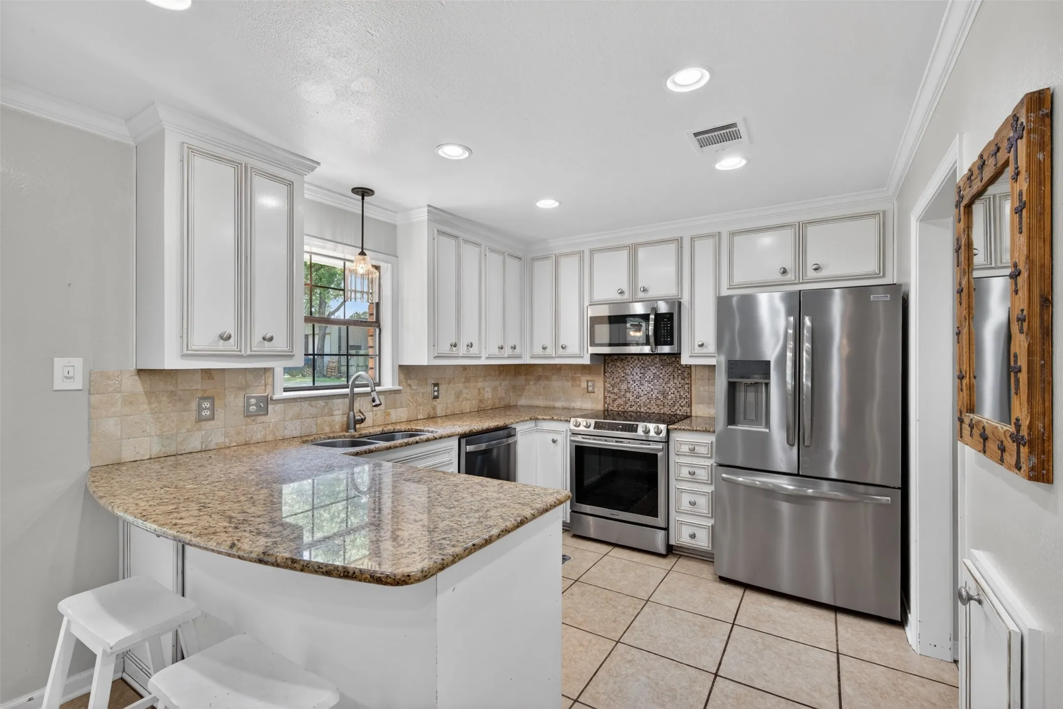 Kitchen featuring white cabinetry, granite countertops, stainless steel appliances, mosaic tile backsplash, and recessed lighting
