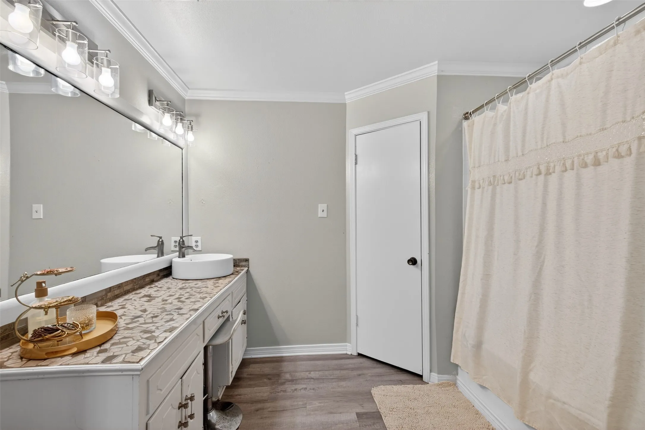 Bathroom featuring a double vanity with vessel sinks, a mosaic tile countertop, and a full-width mirror