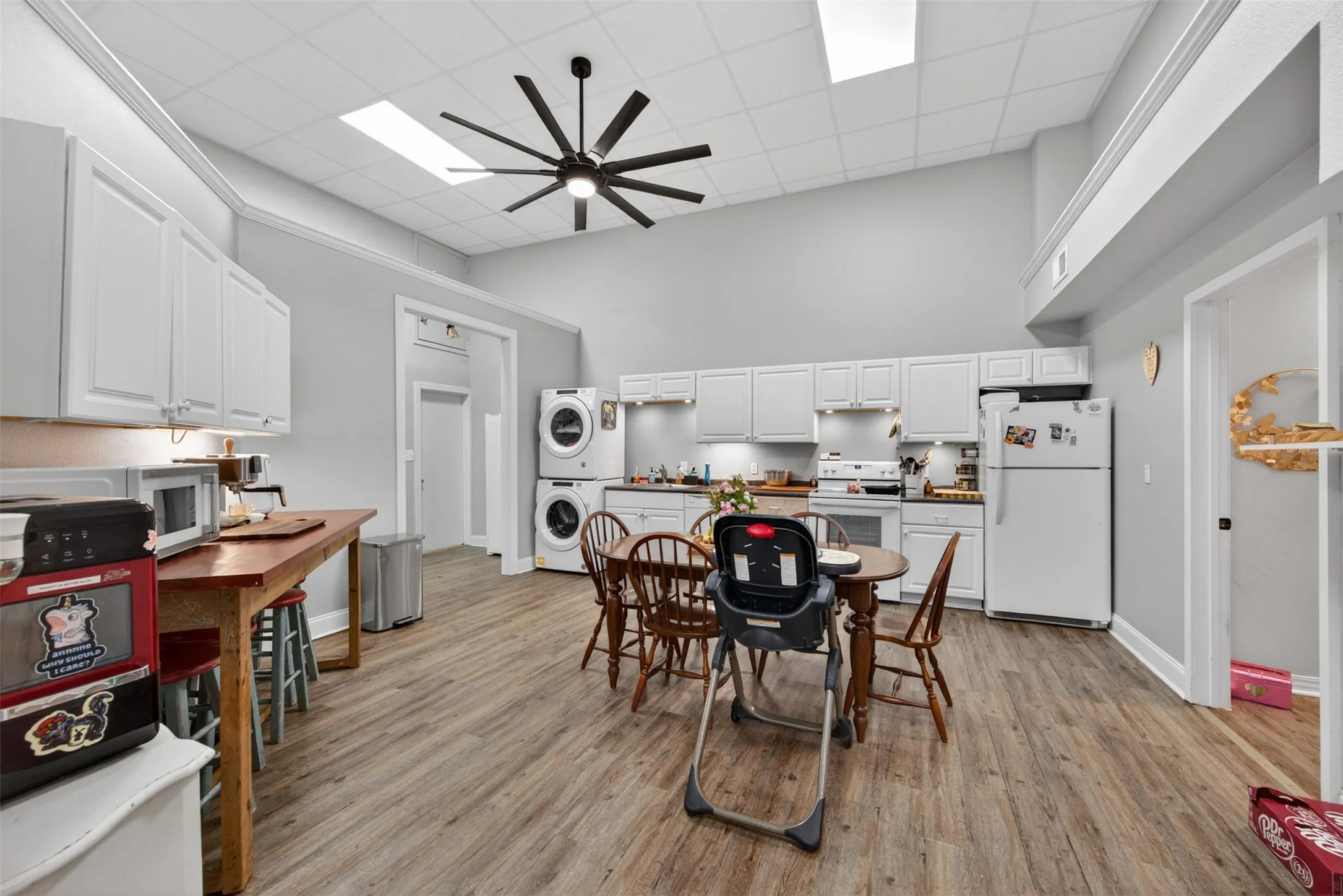 Spacious kitchen featuring plank wood-finish flooring, white cabinetry, a large ceiling fan, and high ceilings