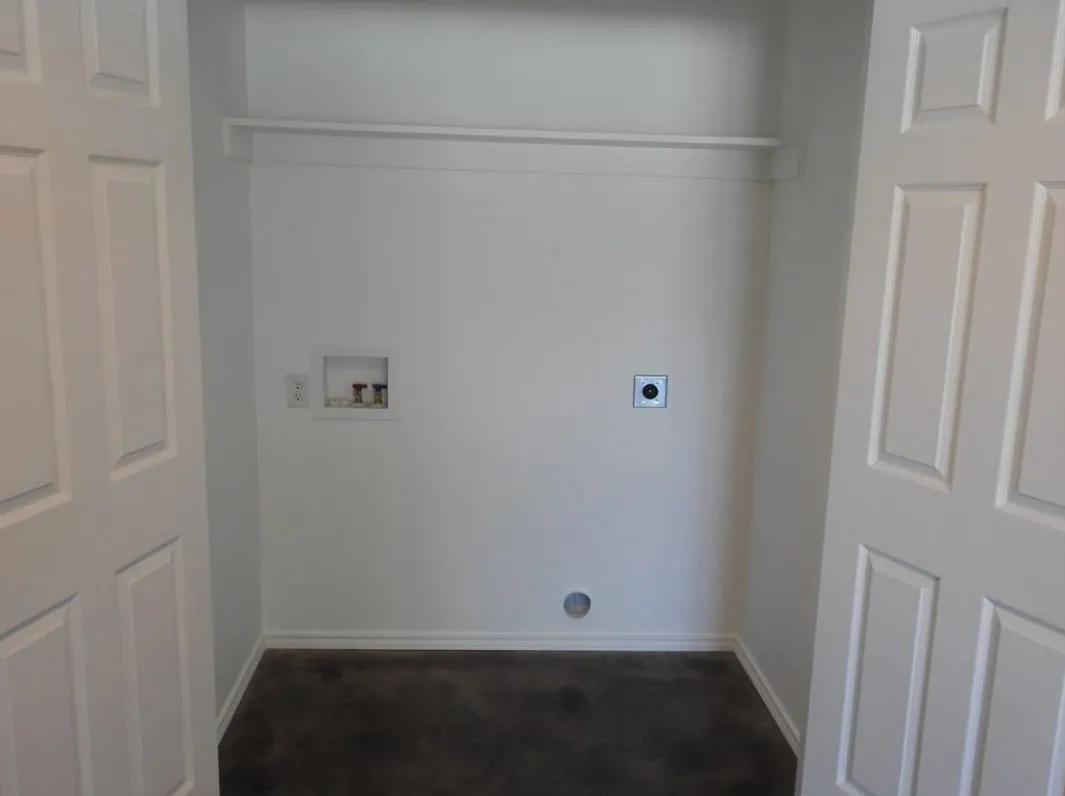 Dedicated utility closet with a white adjustable shelving unit, white baseboards, and a dark floor