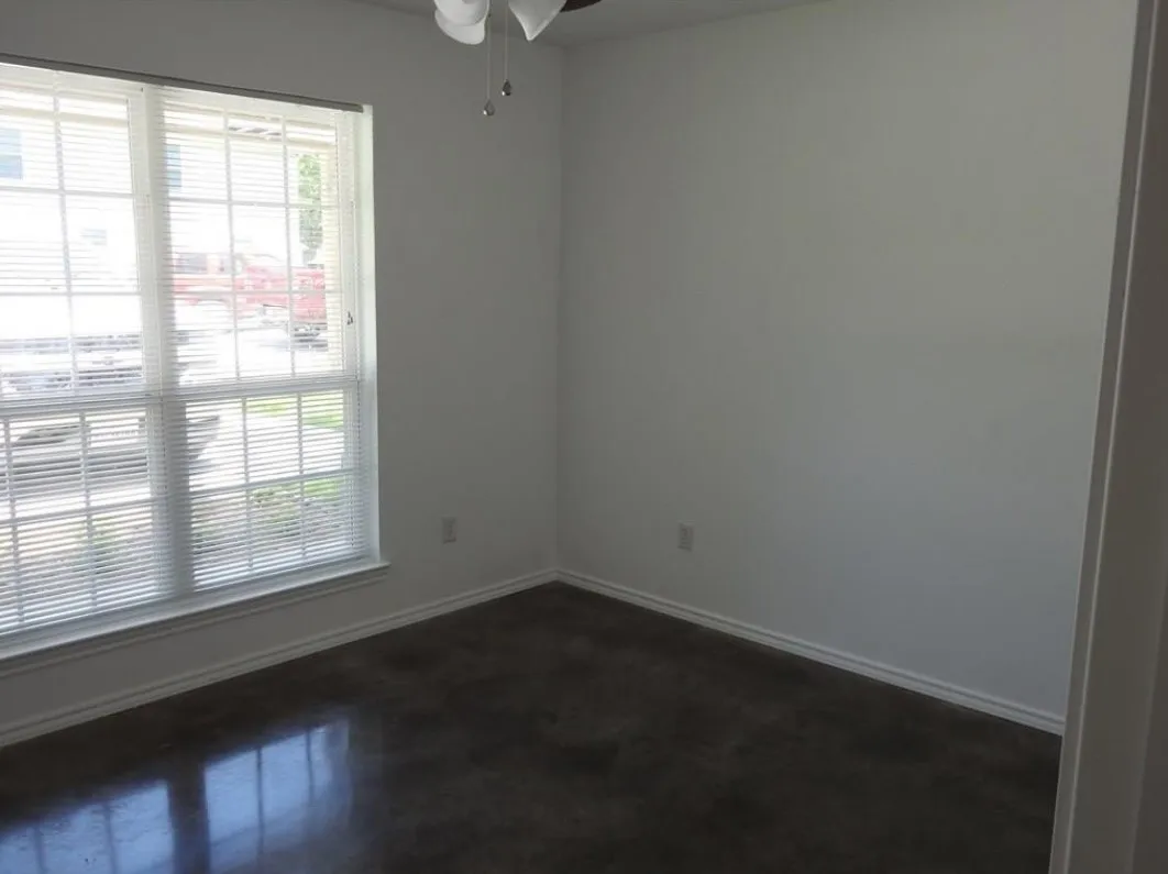 Room with a large window featuring horizontal blinds, a ceiling fan, and dark-finish flooring