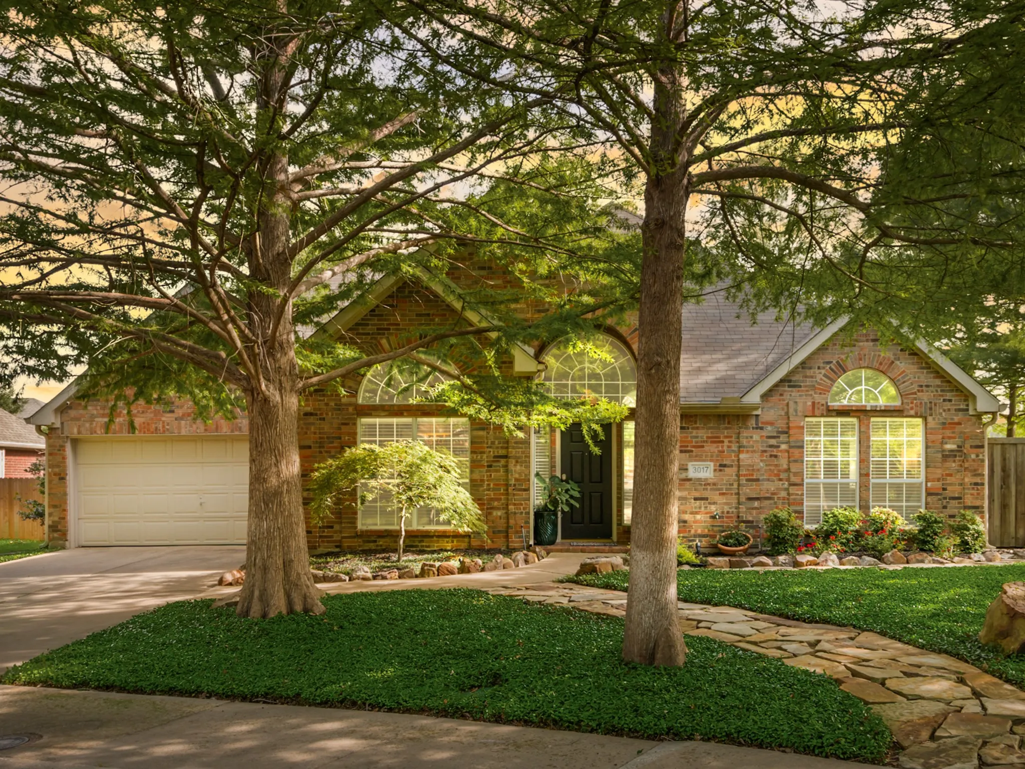 Brick exterior with arched windows, a two-car garage, and a flagstone pathway