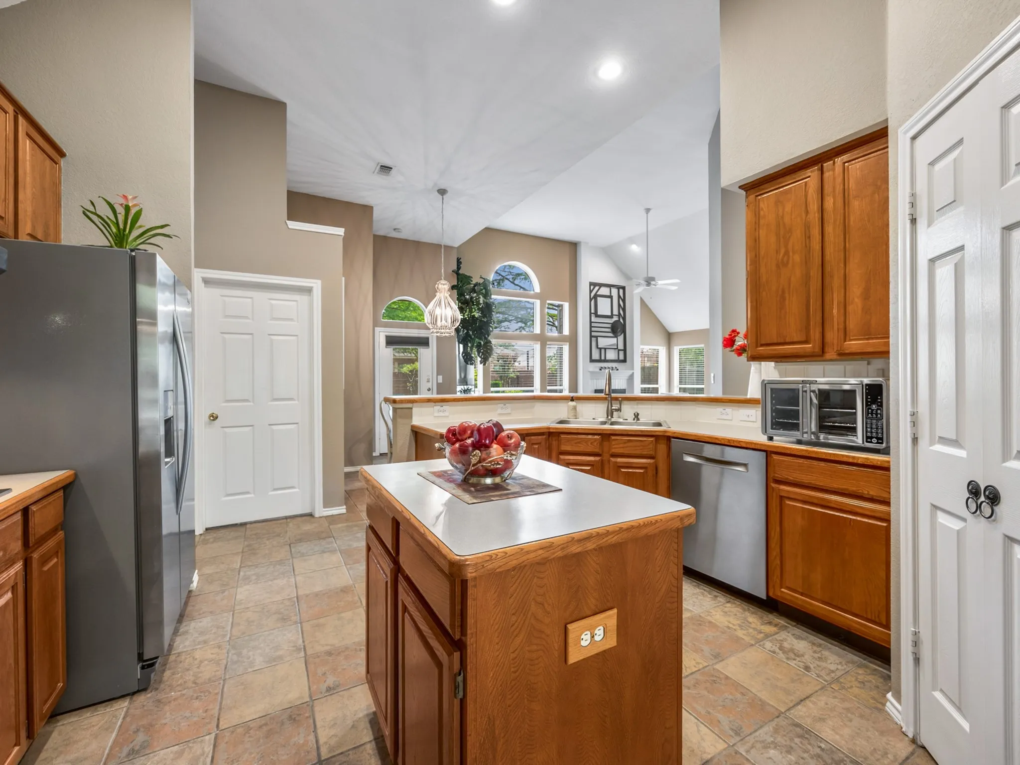 Kitchen featuring a central island with countertop, stainless steel appliances, wood cabinetry, and a tile floor