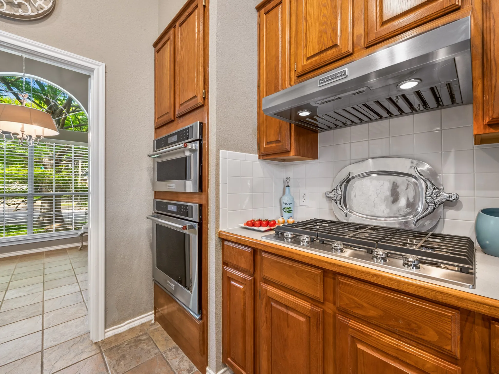 Kitchen featuring a gas cooktop, stainless steel range hood, double wall ovens, and wood cabinetry