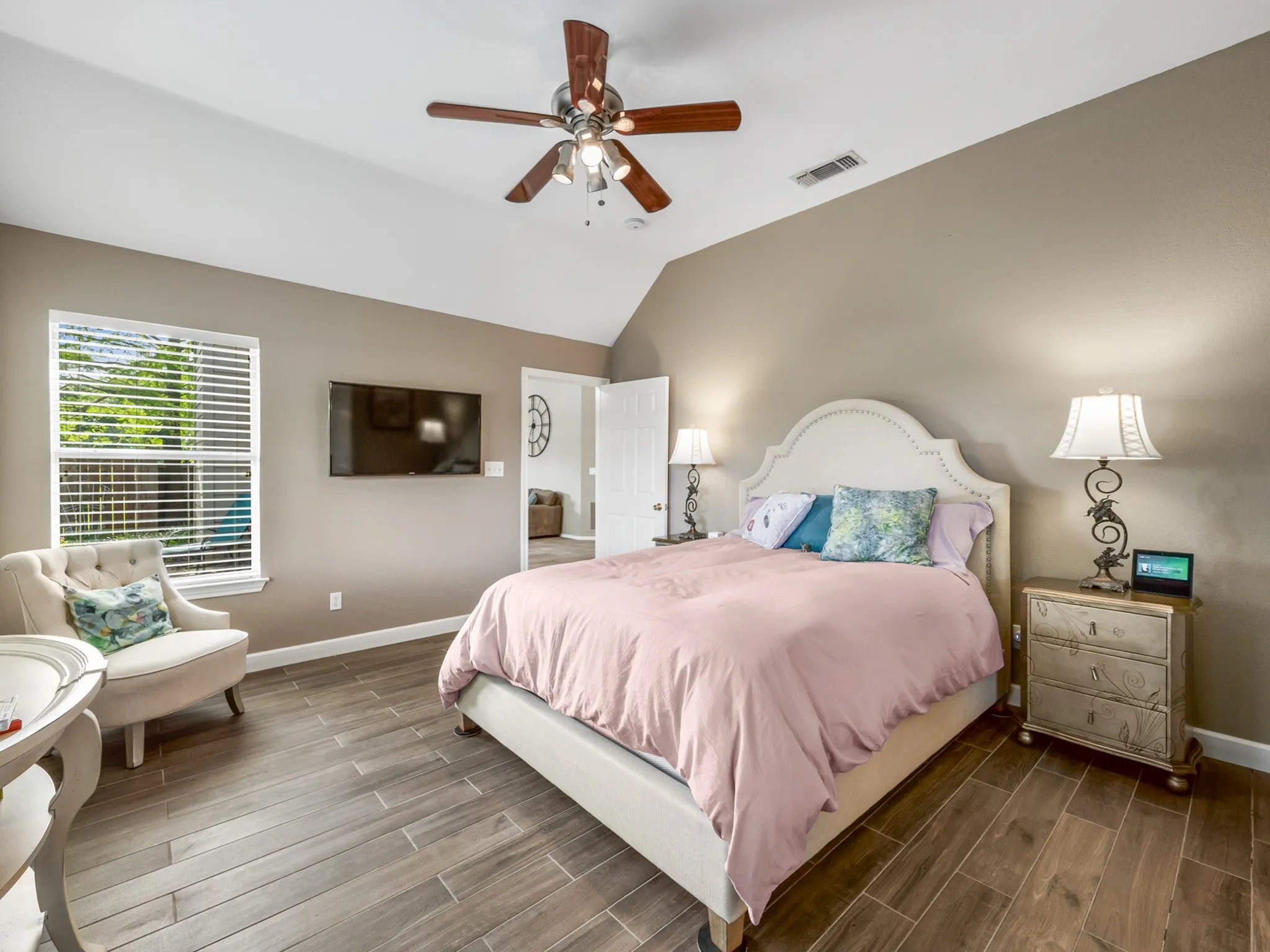 Vaulted ceiling bedroom featuring wood-finish flooring, a window with blinds, and a ceiling fan