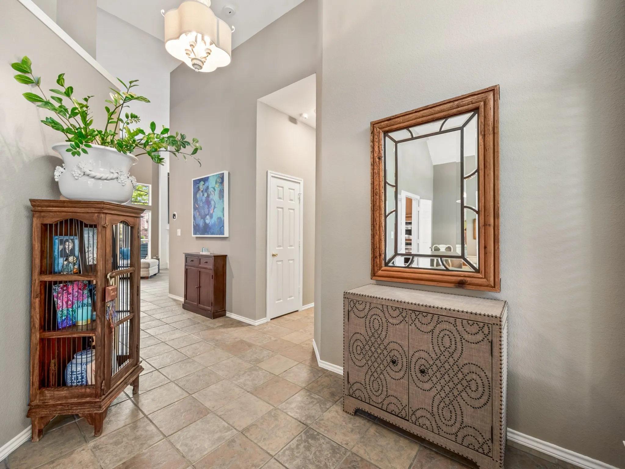 Entryway featuring tile flooring, neutral wall tones, vaulted ceilings, and a decorative light fixture
