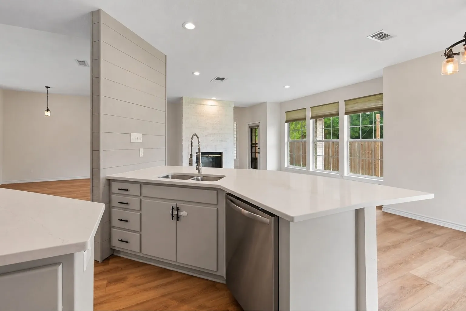 Kitchen island with white countertop, integrated double sink, and stainless steel dishwasher