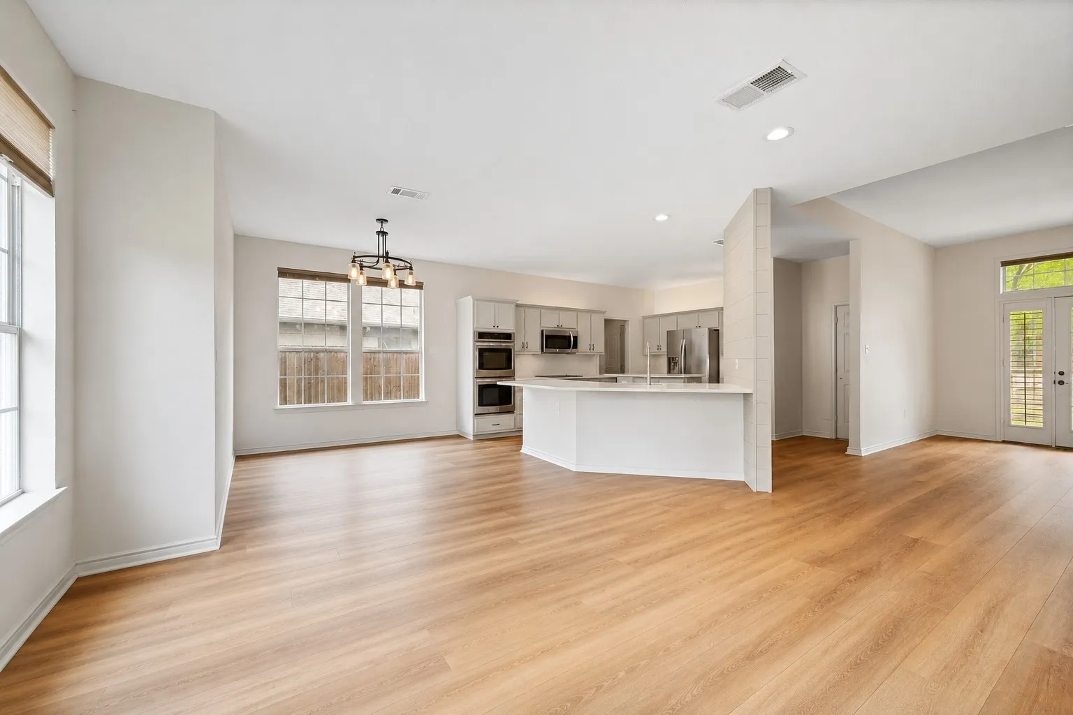Open-concept living area featuring wood-finish flooring, recessed lighting, and a contemporary chandelier